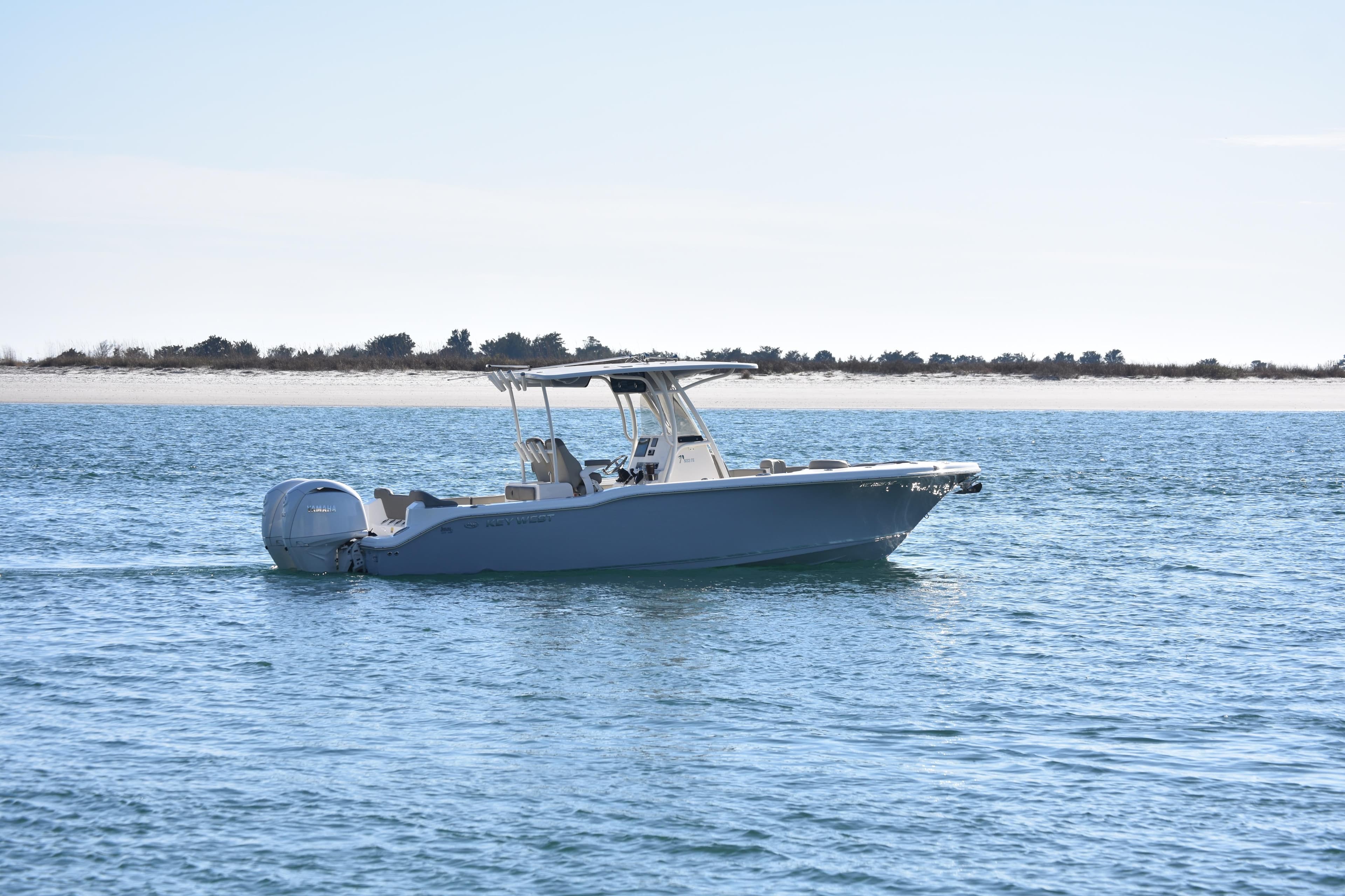 2024 Key West 263 FS boat cruising on calm blue waters near a sandy shoreline.
