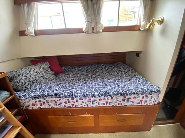 Cozy cabin bed in 1973 Grand Banks 42 Classic yacht with patterned bedding and wooden storage.
