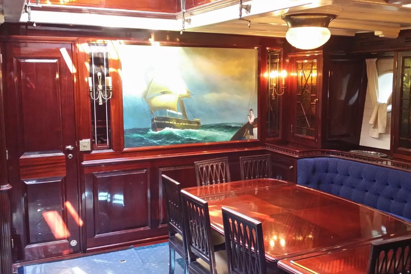 Luxurious wooden interior of 1930 Frederikksund Gaff Topsail Schooner with nautical painting.