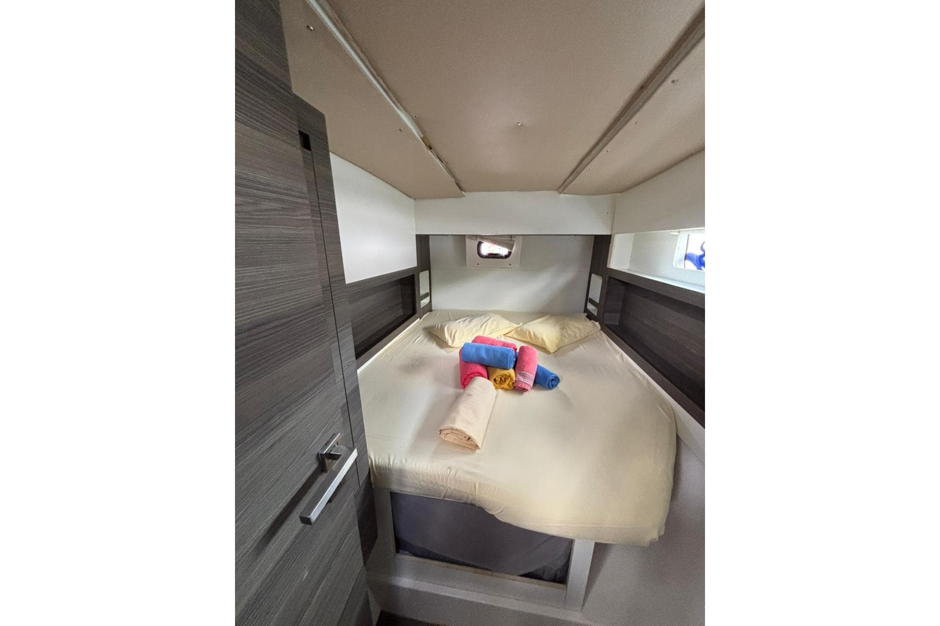 Cabin interior of 2015 Nautitech 40 Open catamaran with cozy bed and colorful towels.