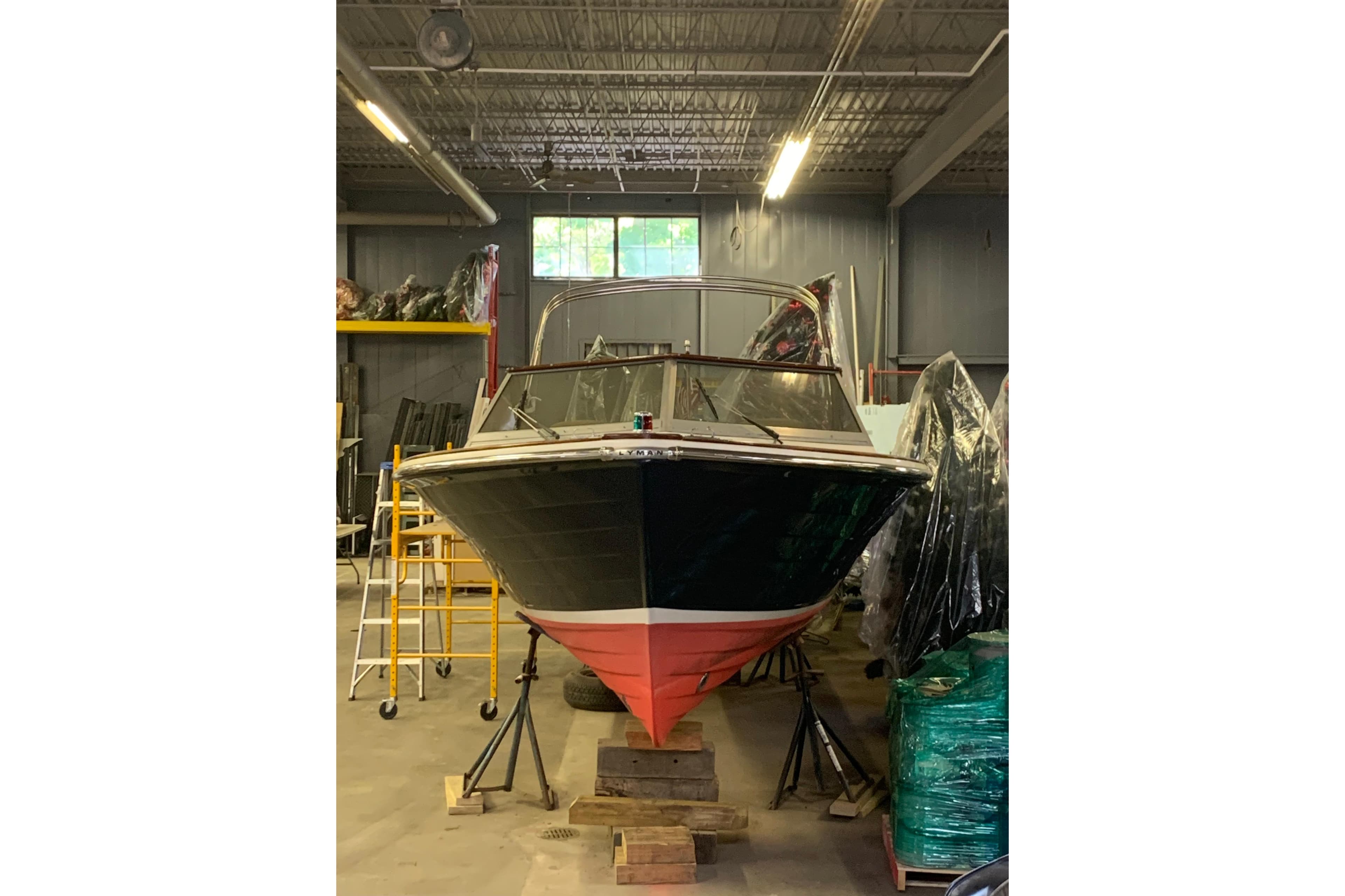 1973 Lyman Islander boat in storage, elevated on blocks, in a warehouse setting.