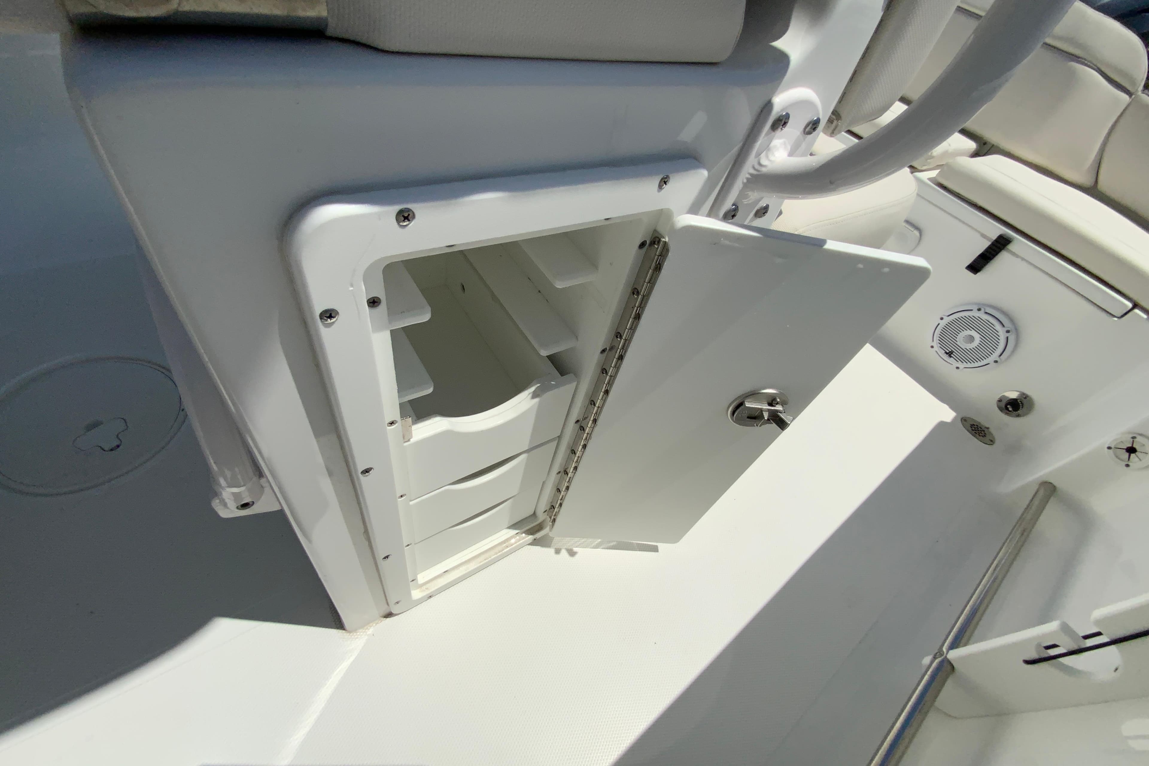 Open storage compartment on 2024 Sea Hunt Ultra 234 boat, showcasing interior space.