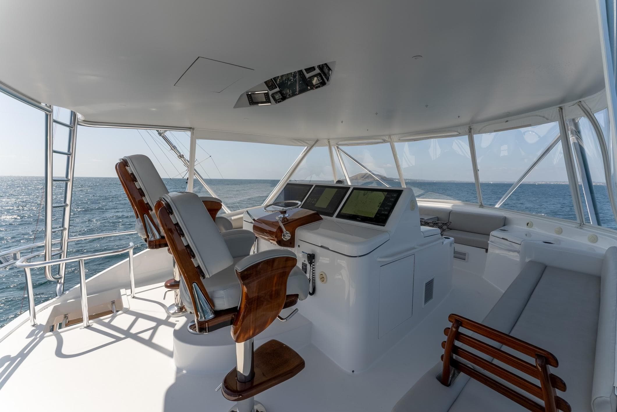 2018 Hatteras GT70 yacht helm with ocean view, featuring modern navigation equipment and seating.