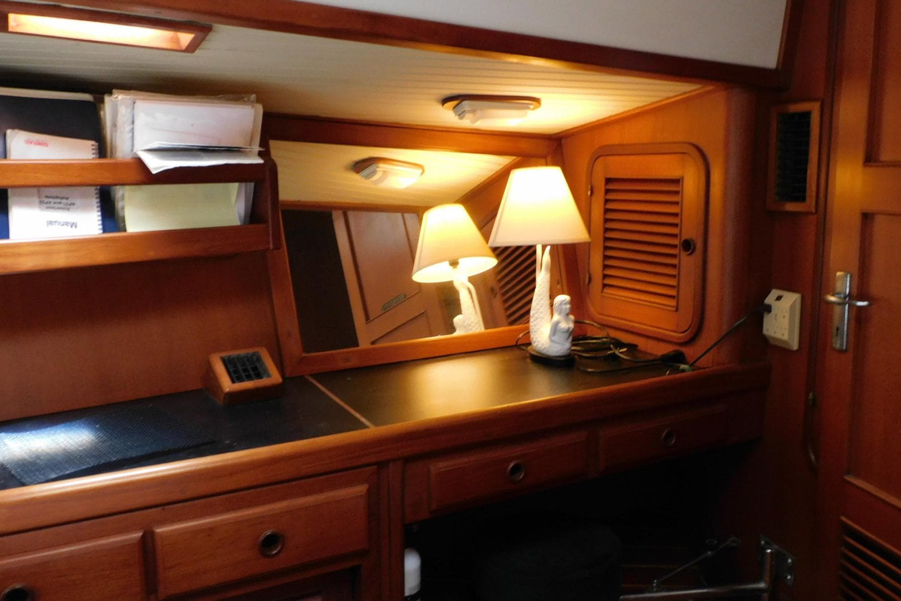 Cozy cabin interior of 1988 Hans Christian 45 Independence Trawler with wooden furnishings and lamp.