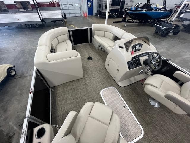 2017 Harris Cruiser 200 pontoon boat interior with beige seating and steering console in a showroom.