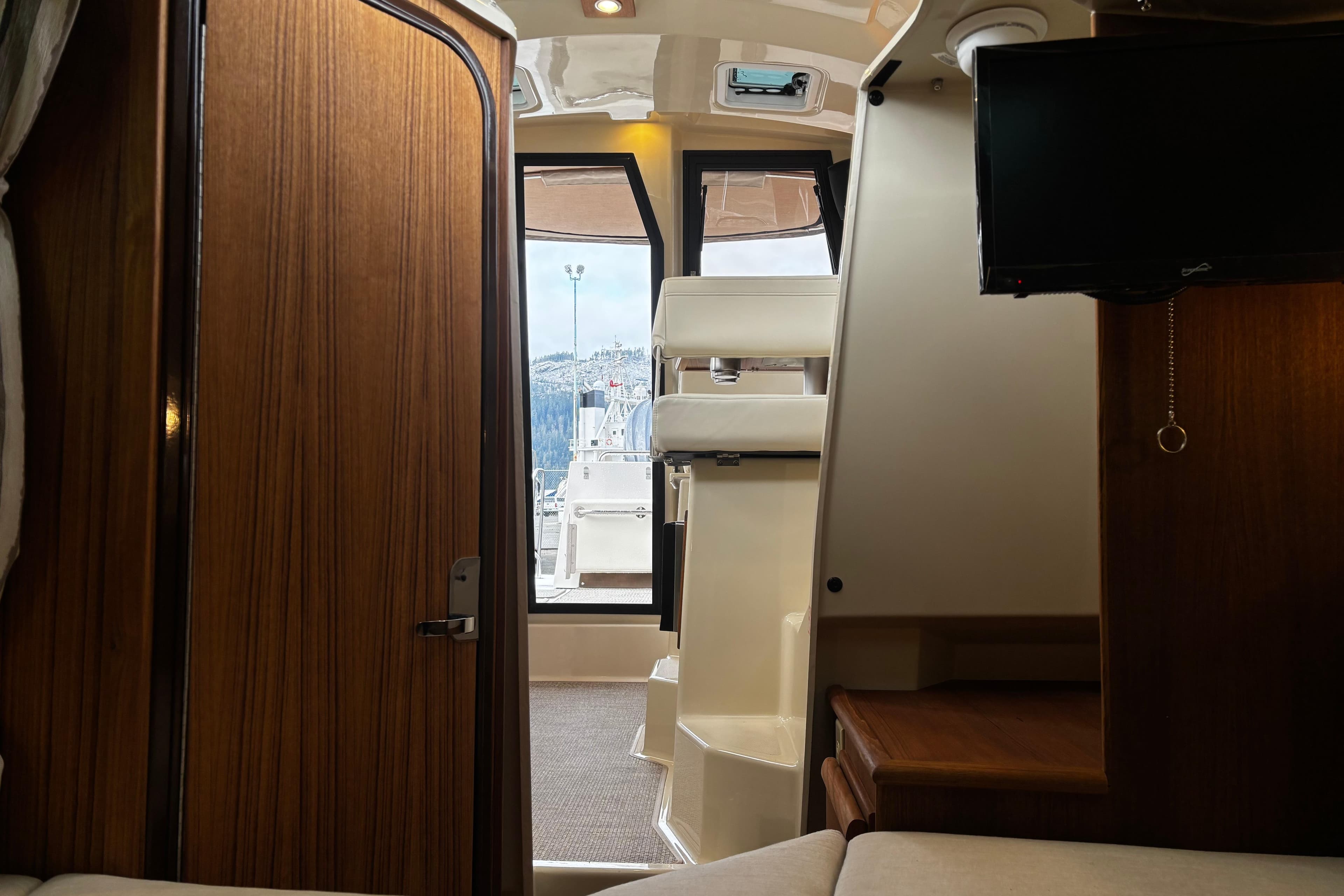 Interior view of 2026 Ranger Tugs R-25 boat, featuring wood paneling and a mounted TV.