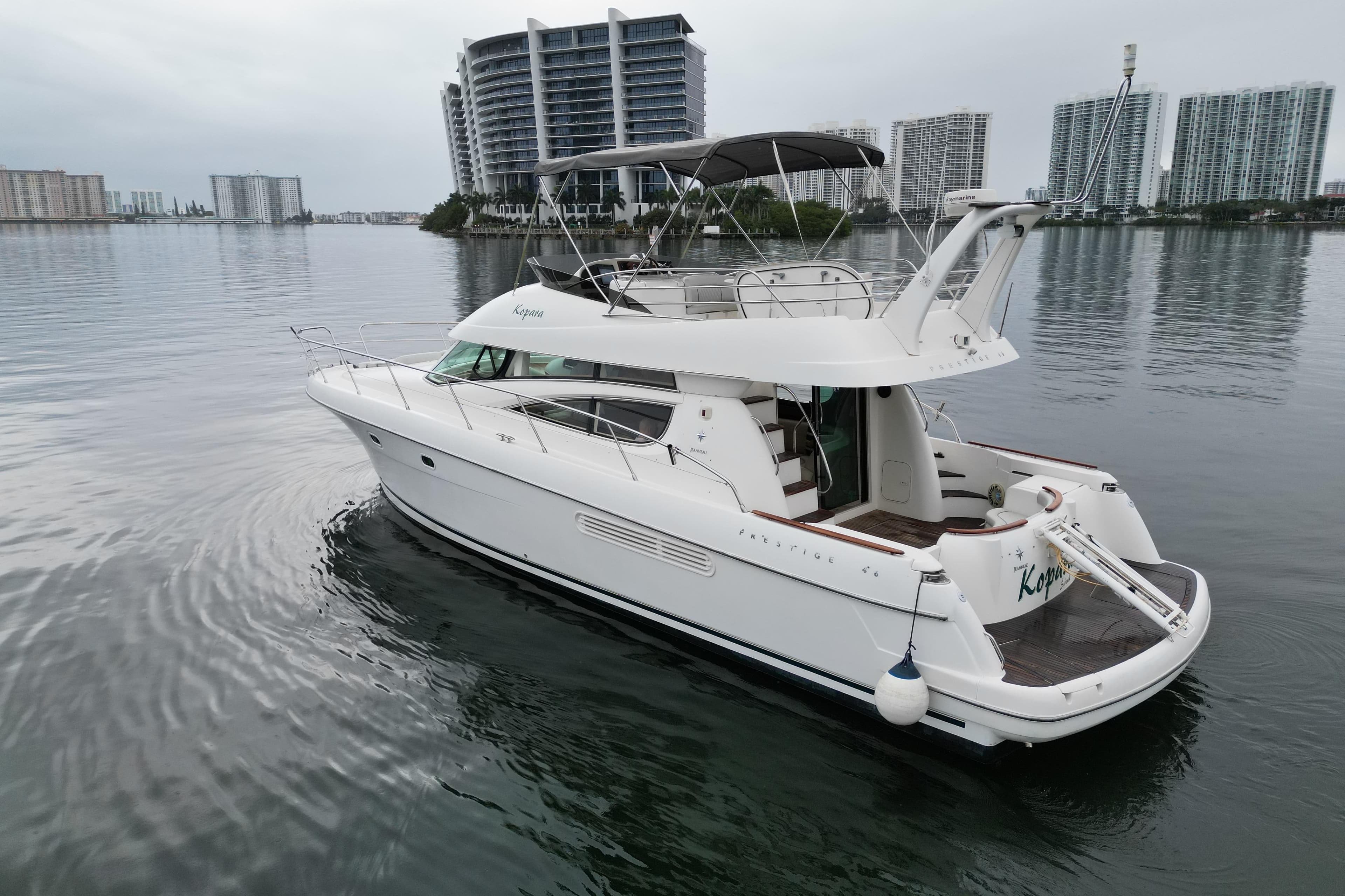 2005 Prestige 46 yacht on calm water with city skyline backdrop.