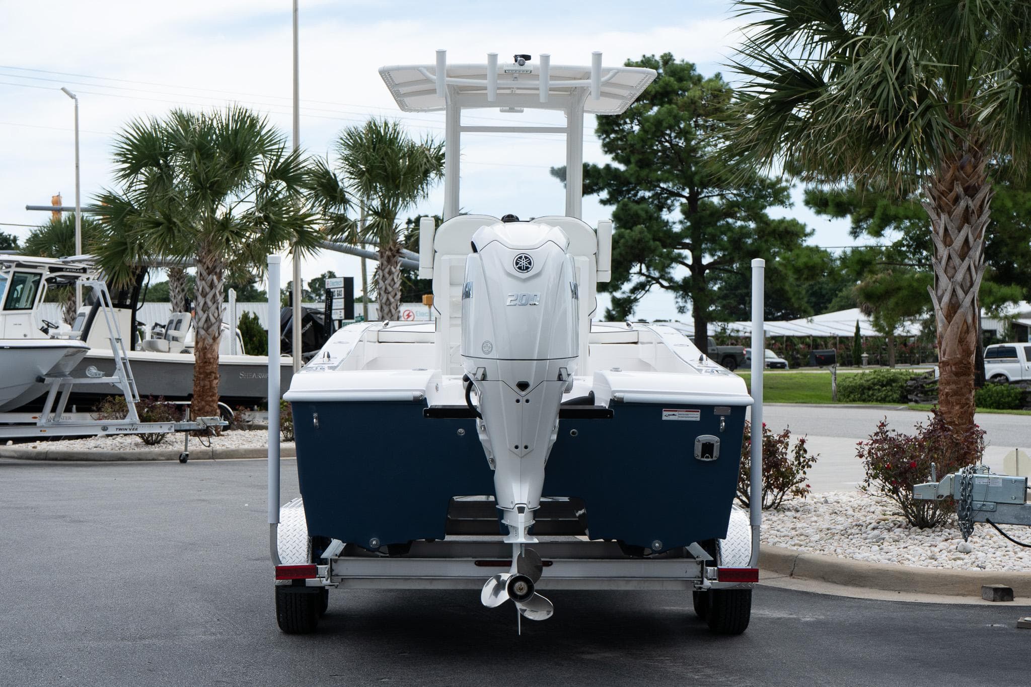 2026 Twin Vee 22 Bay Cat boat on trailer, parked near palm trees.