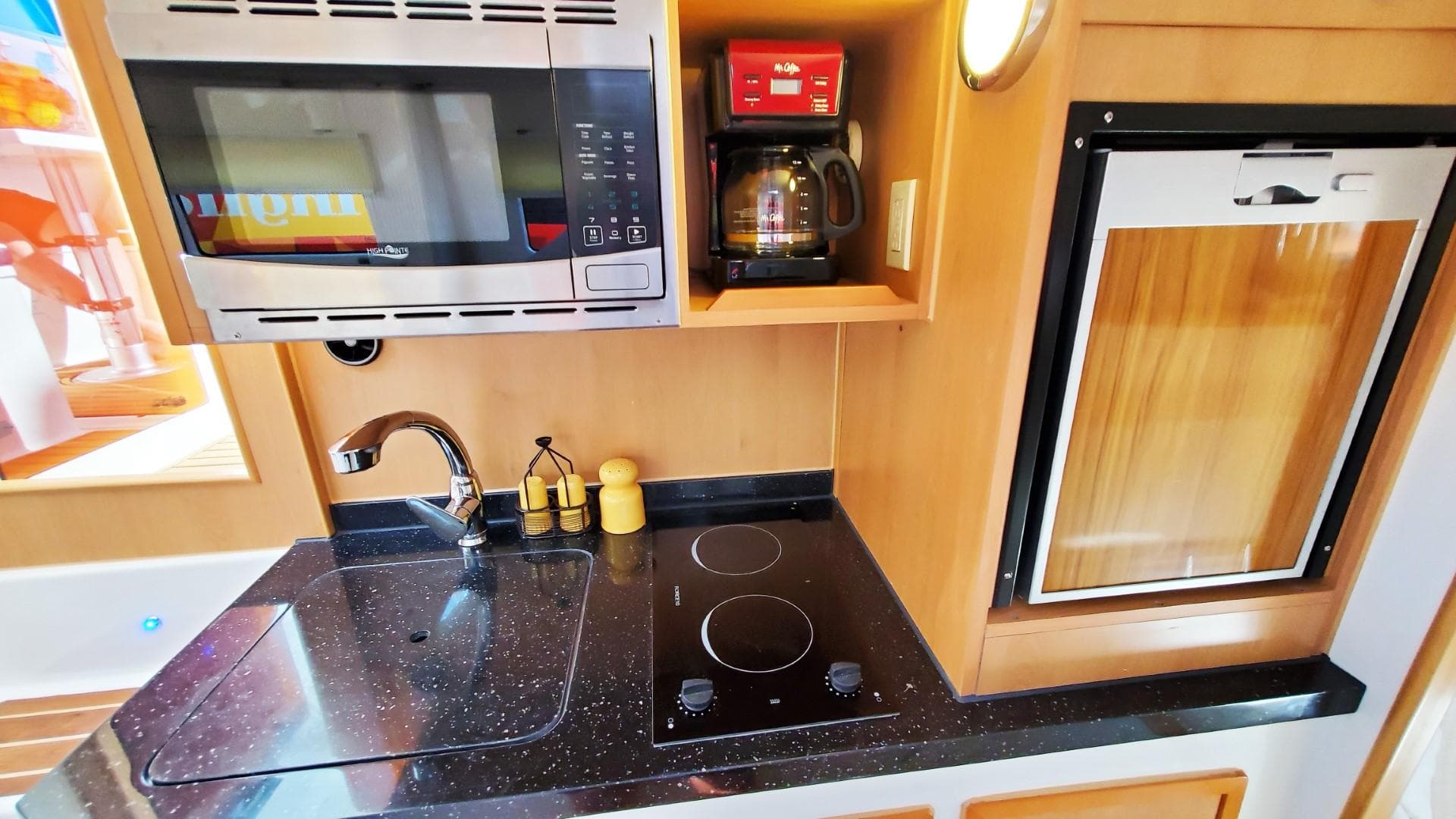 Compact kitchen in Smart Cat E280 Electric 2025, featuring stove, microwave, and coffee maker.