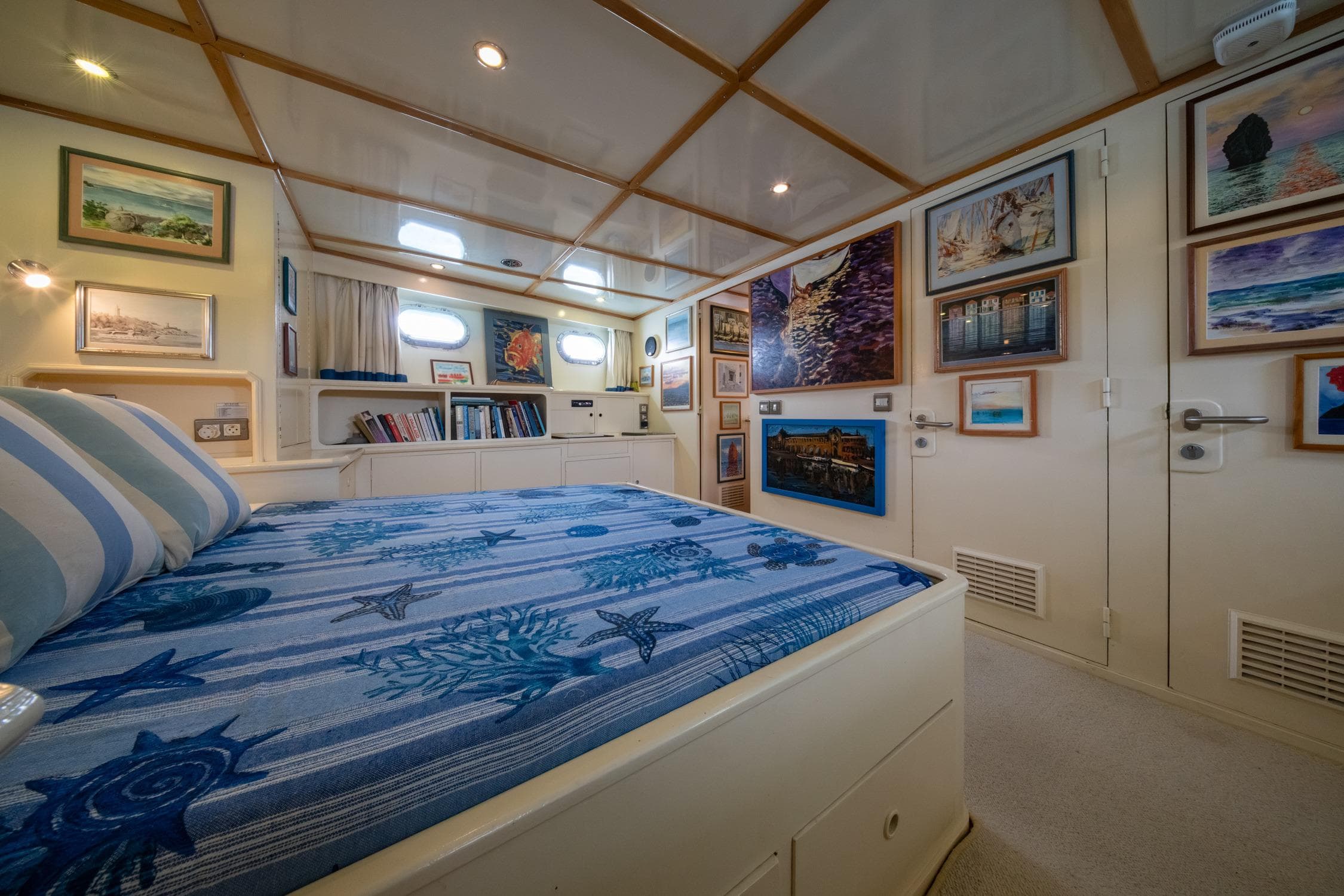 Luxurious 1972 Custom Siccna yacht bedroom with nautical decor and framed artwork.