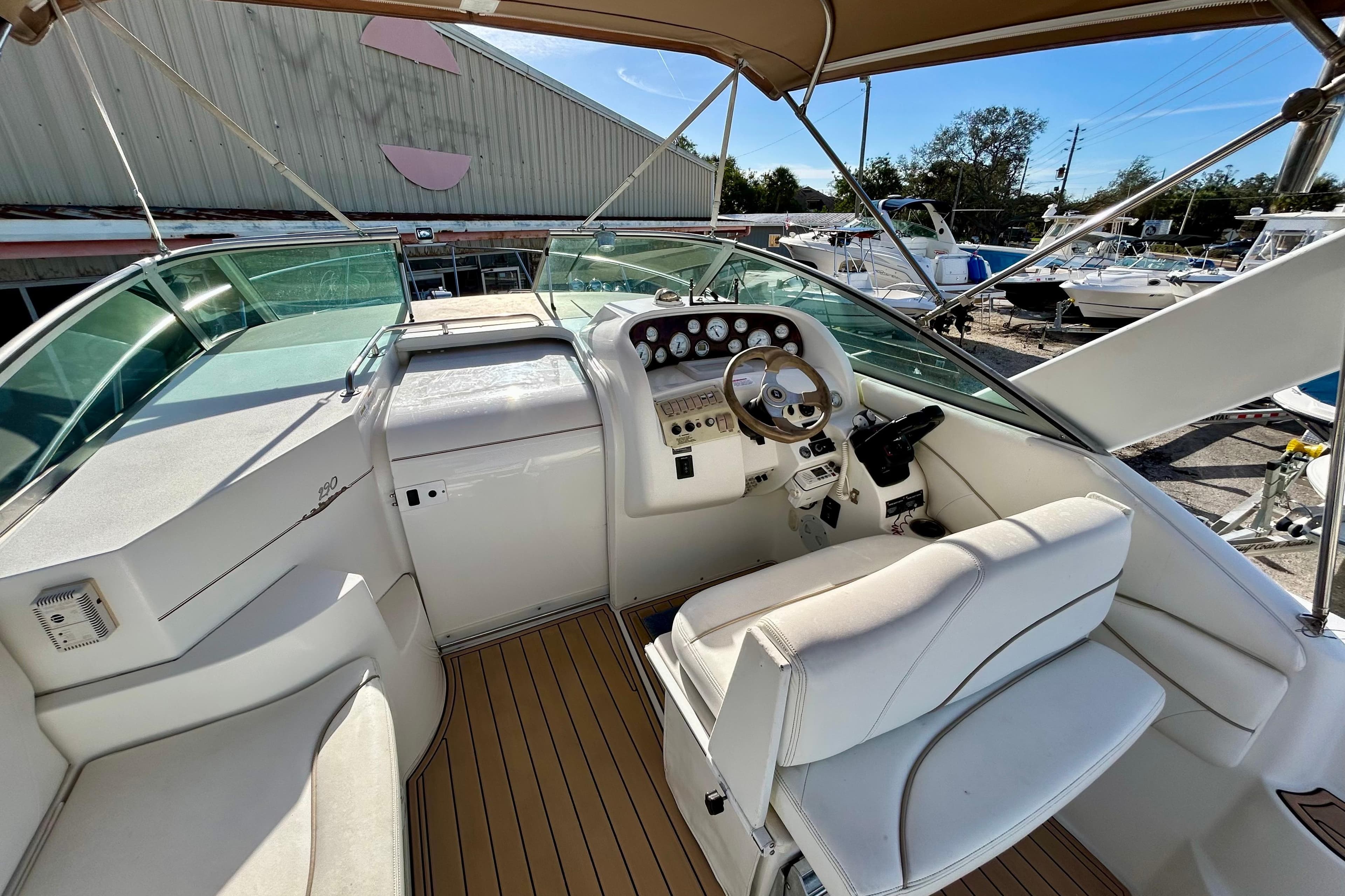 2000 Larson 290 Cabrio boat cockpit with steering wheel and seating, docked outdoors.