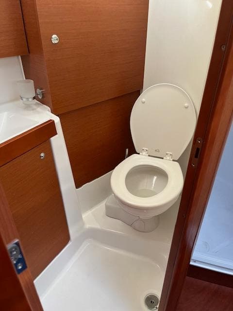 2017 Beneteau Oceanis 38.1 yacht bathroom with wooden cabinetry and white toilet.
