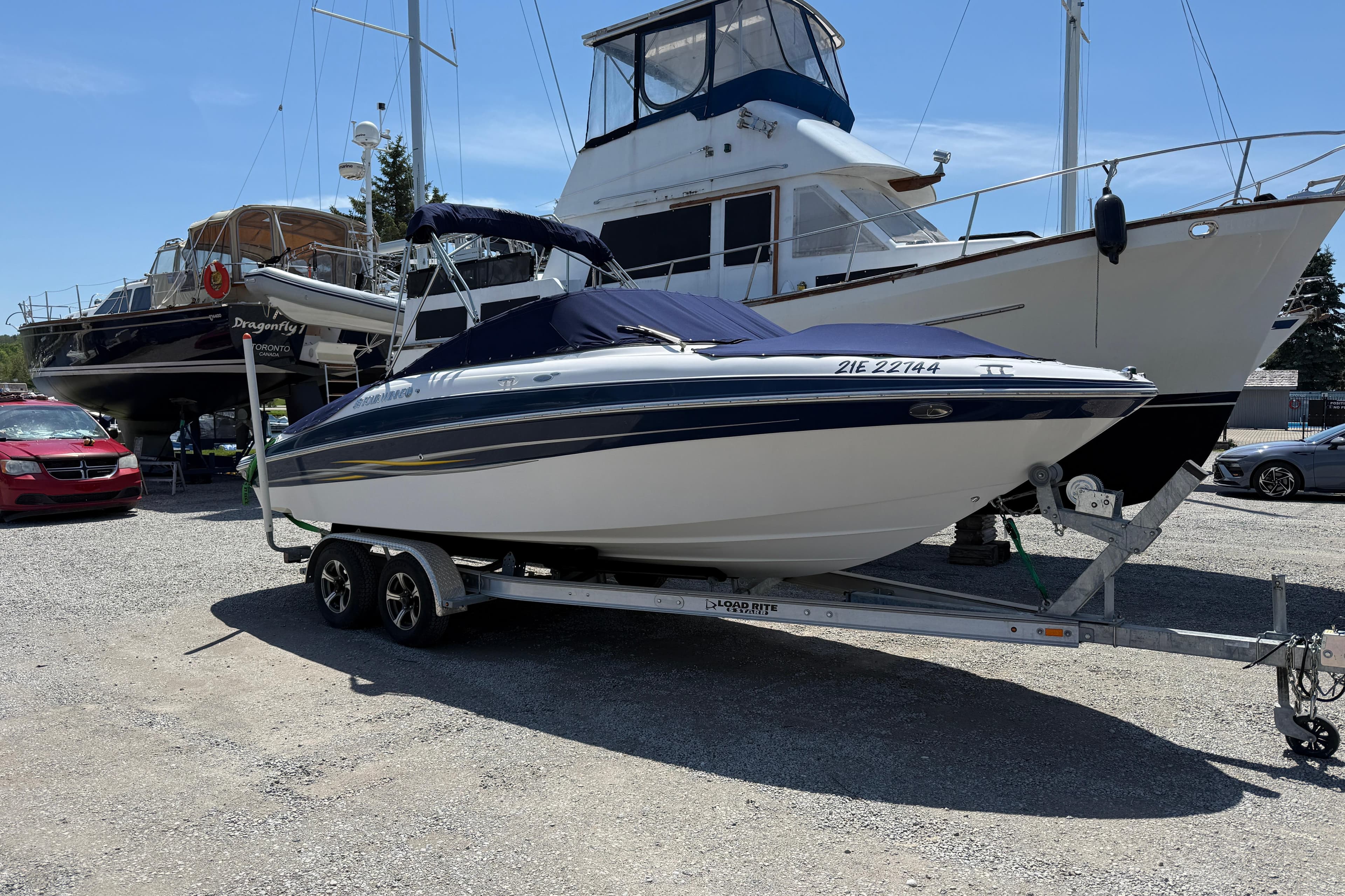 2005 Four Winns 230 Horizon boat on trailer, parked in marina with other boats.