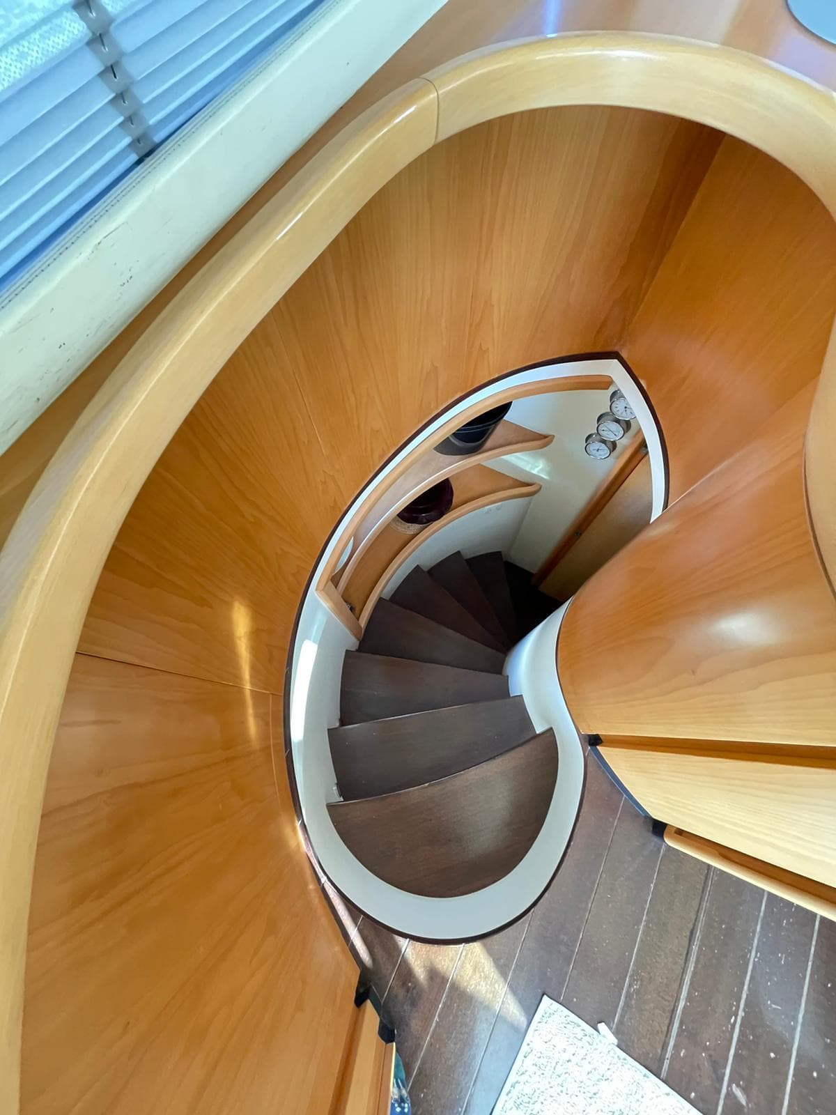 Curved wooden staircase inside 2005 Pershing 76 yacht, featuring sleek design and modern finish.