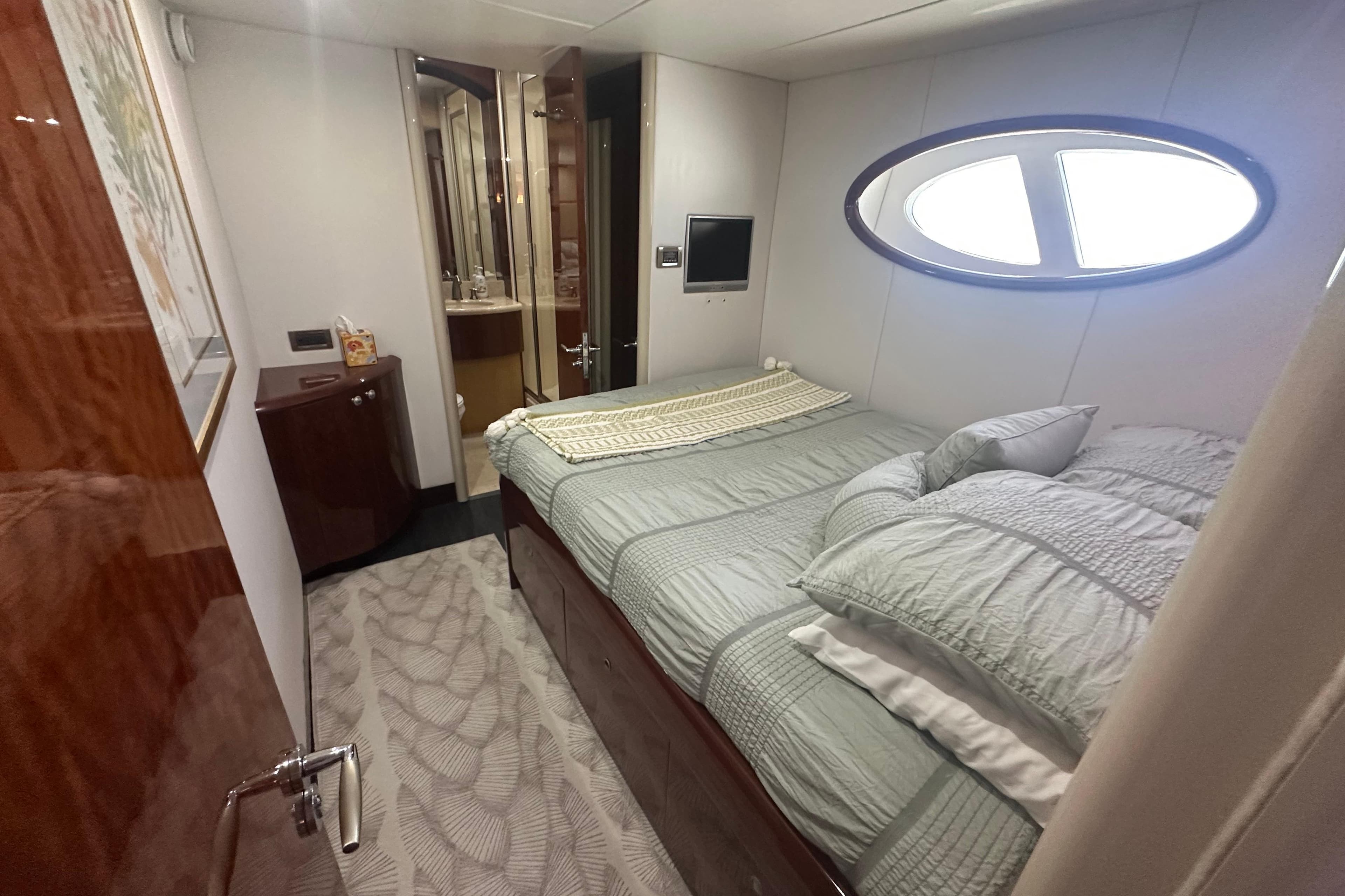 Luxurious bedroom in a 2006 Lazzara 68 Motoryacht with elegant decor and oval window.