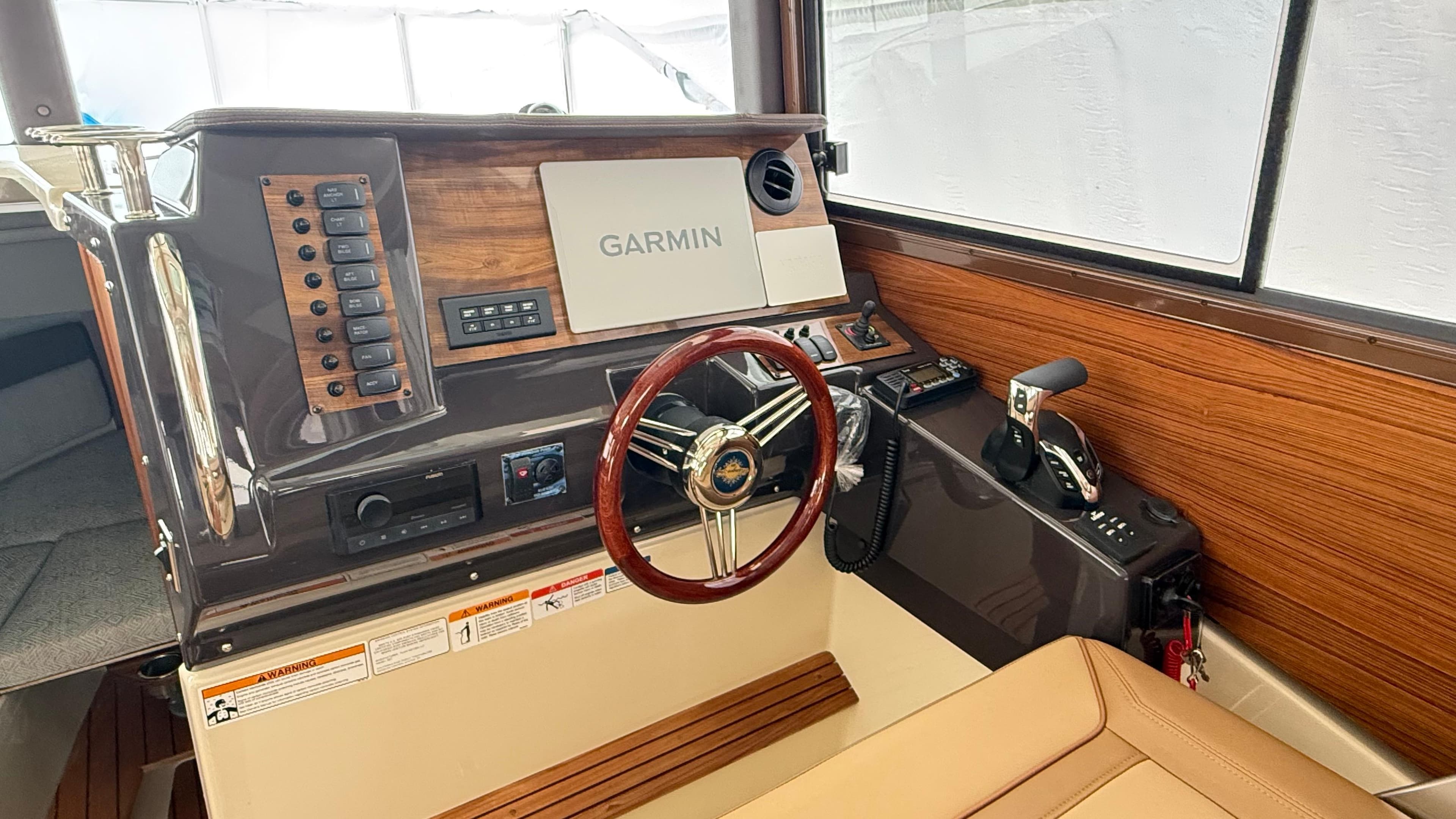 2026 Ranger Tugs R-27 helm with Garmin navigation, wood accents, and leather seating.