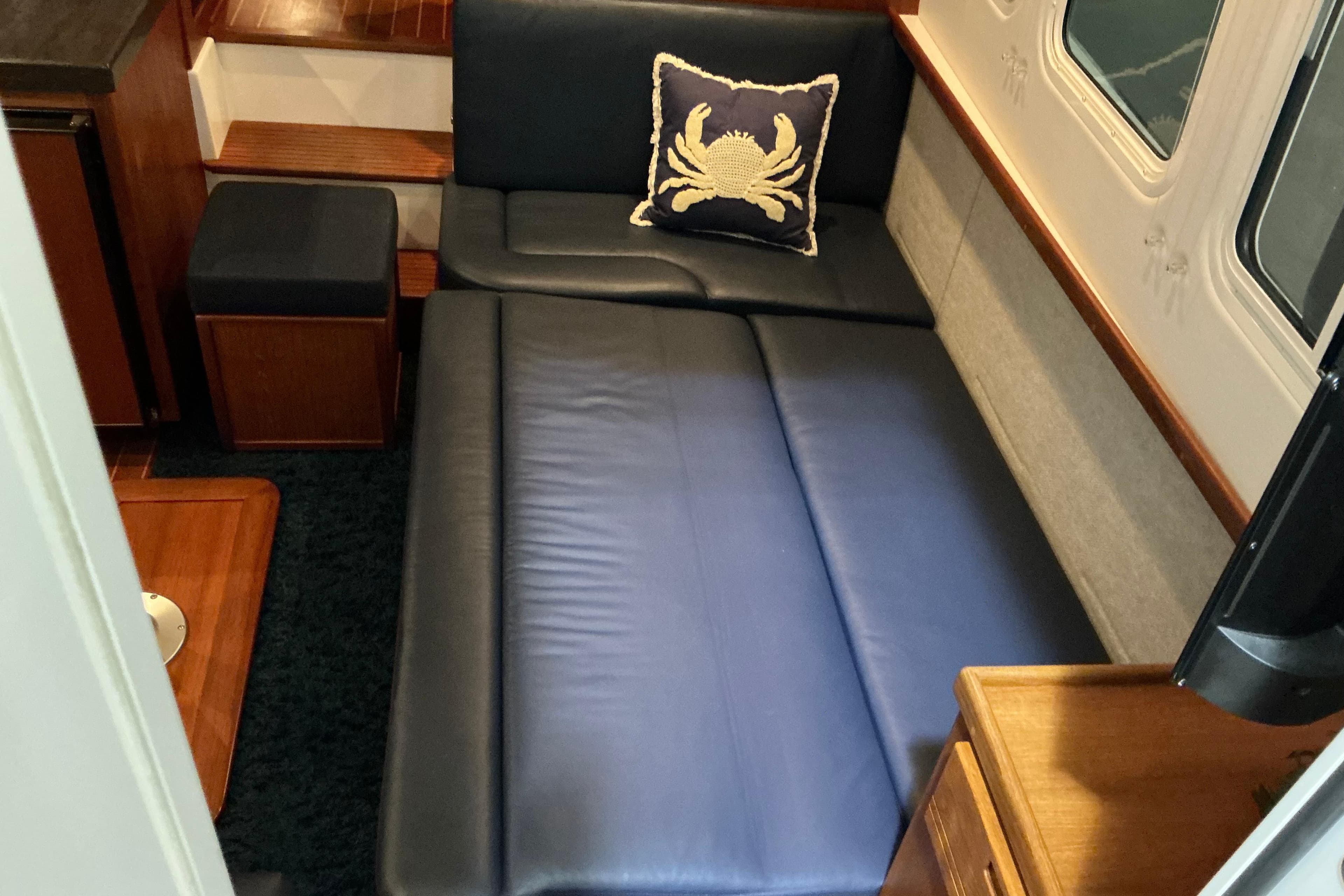 Interior of 2010 Nordic Tug 32 with blue leather seating and crab-themed pillow.