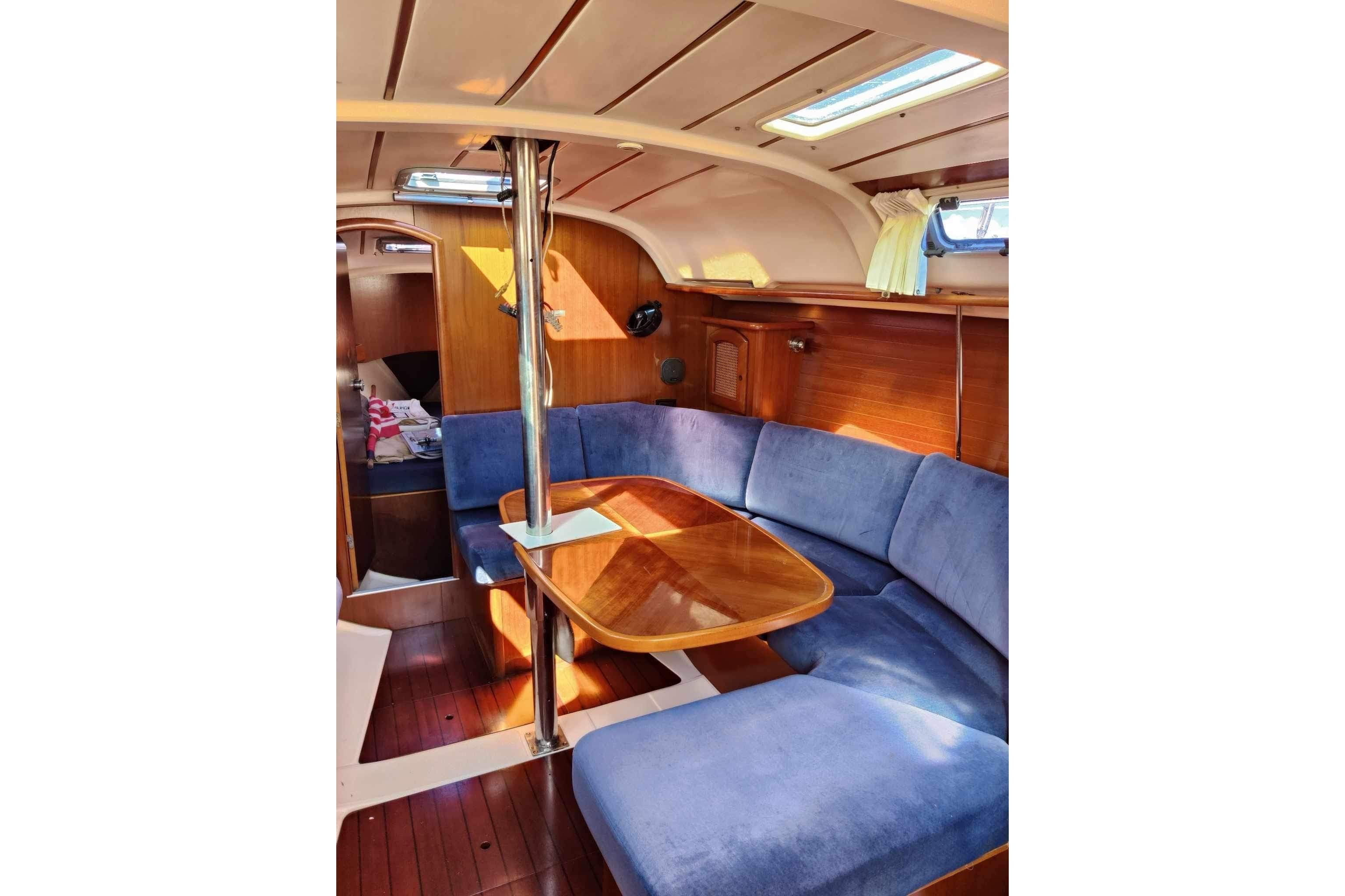 Interior of 1998 Beneteau Oceanis 352 sailboat with blue seating and wooden table.