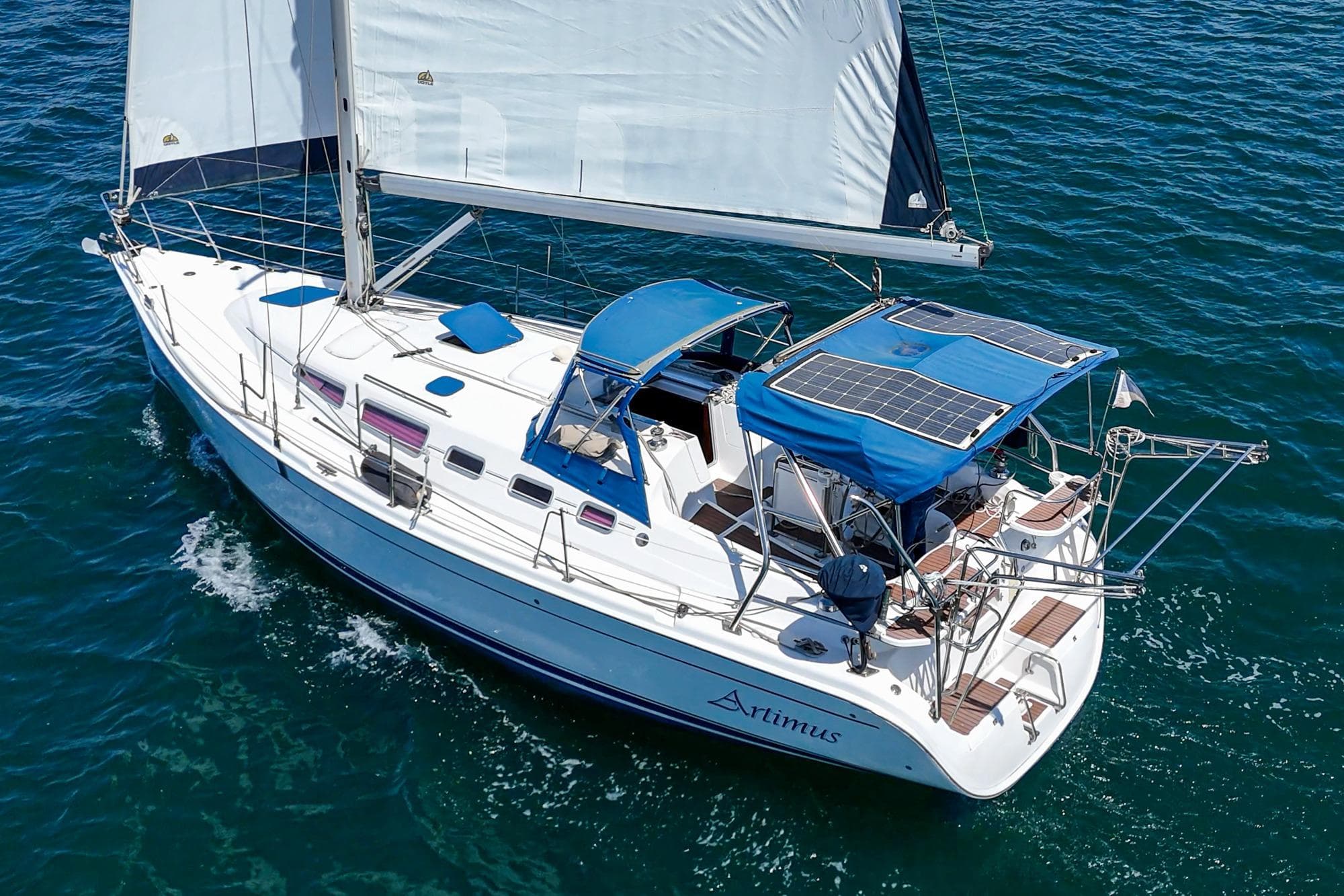Sailing yacht "Artimus," 2007 Hunter 38 model, cruising on open water with solar panels.