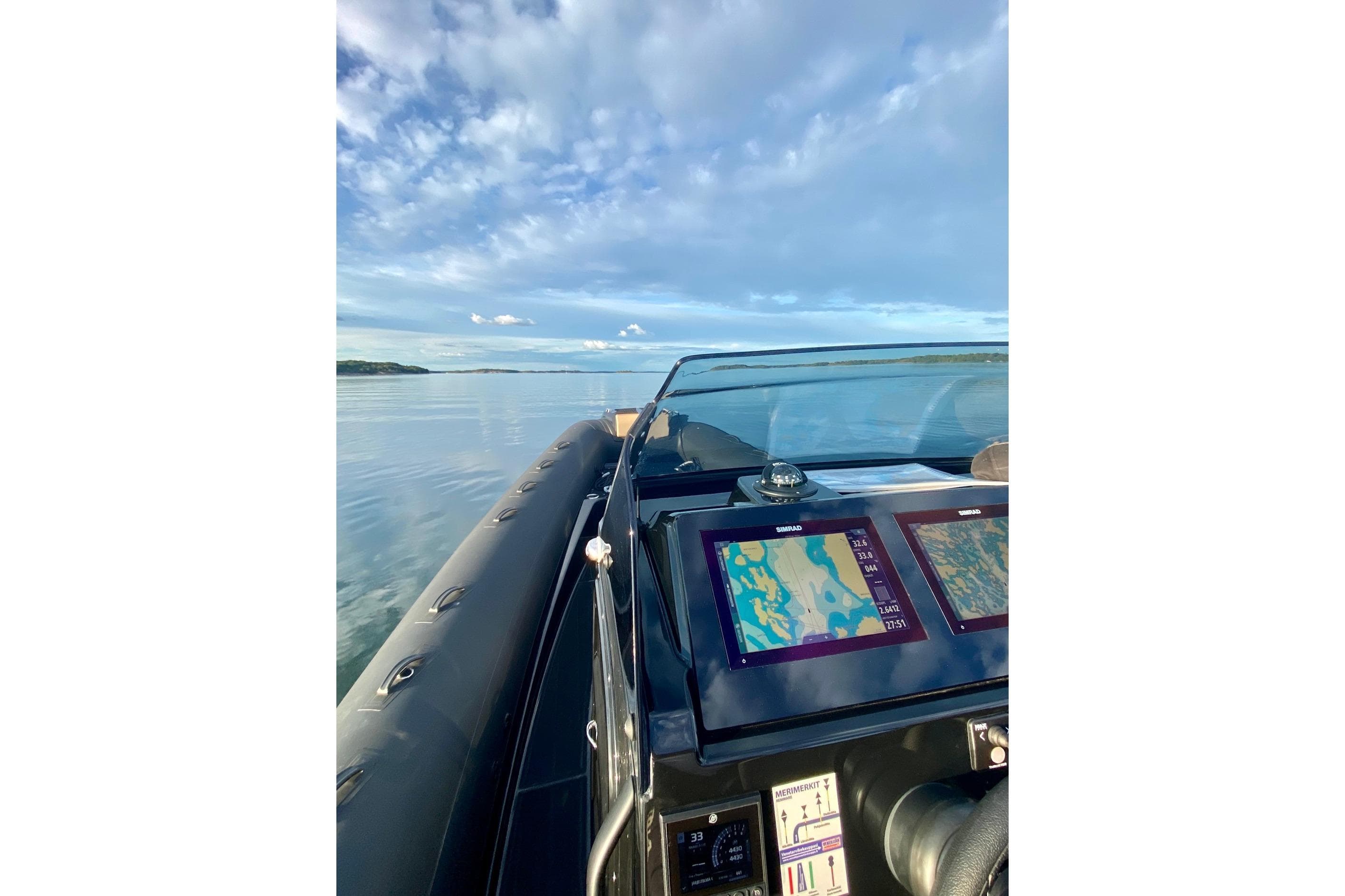 Brig Eagle 10 boat dashboard with navigation screens, cruising on calm waters under a blue sky.