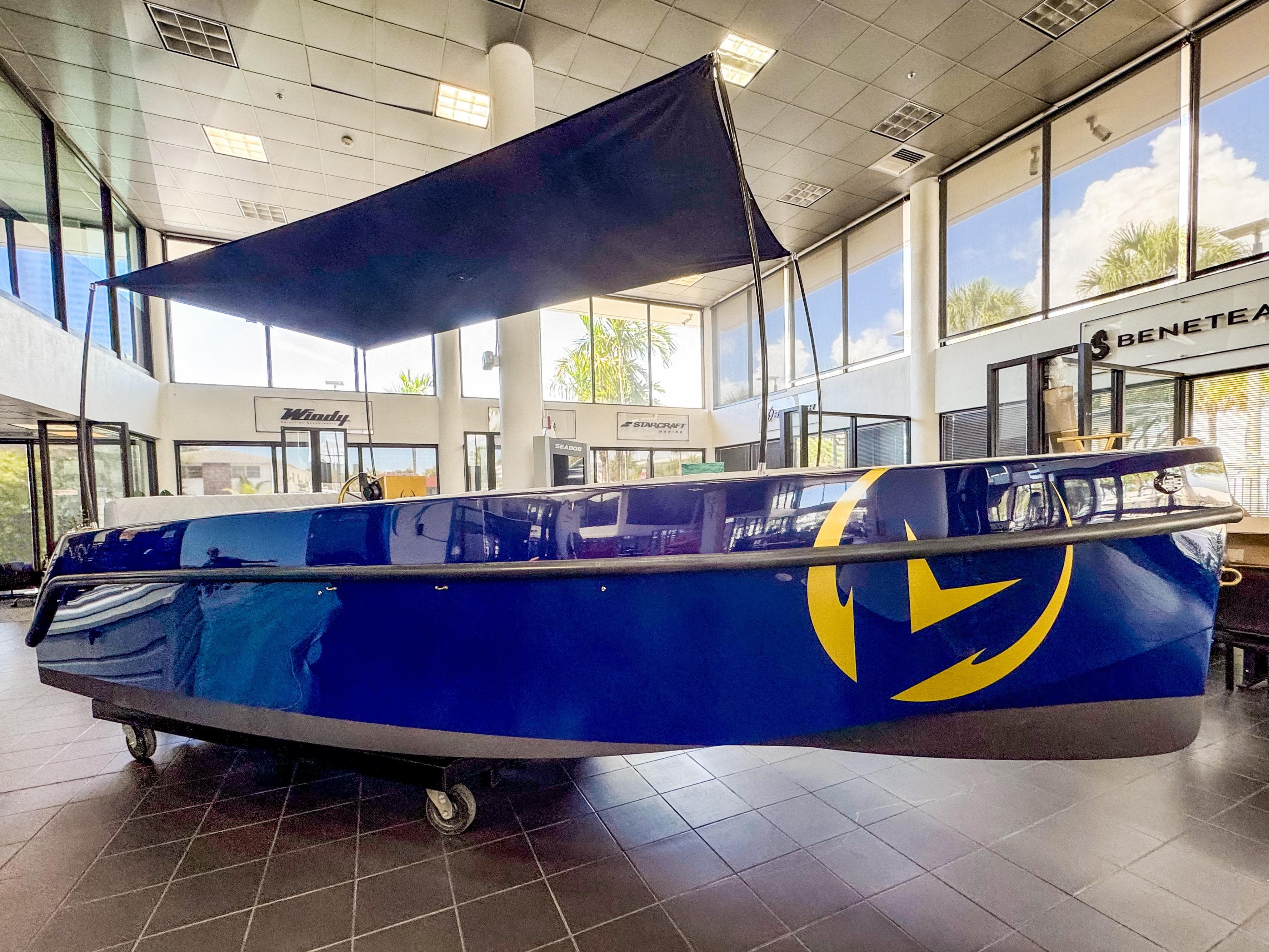 2025 Vision Marine Technologies Volt 180 boat displayed indoors, featuring a sleek blue design.