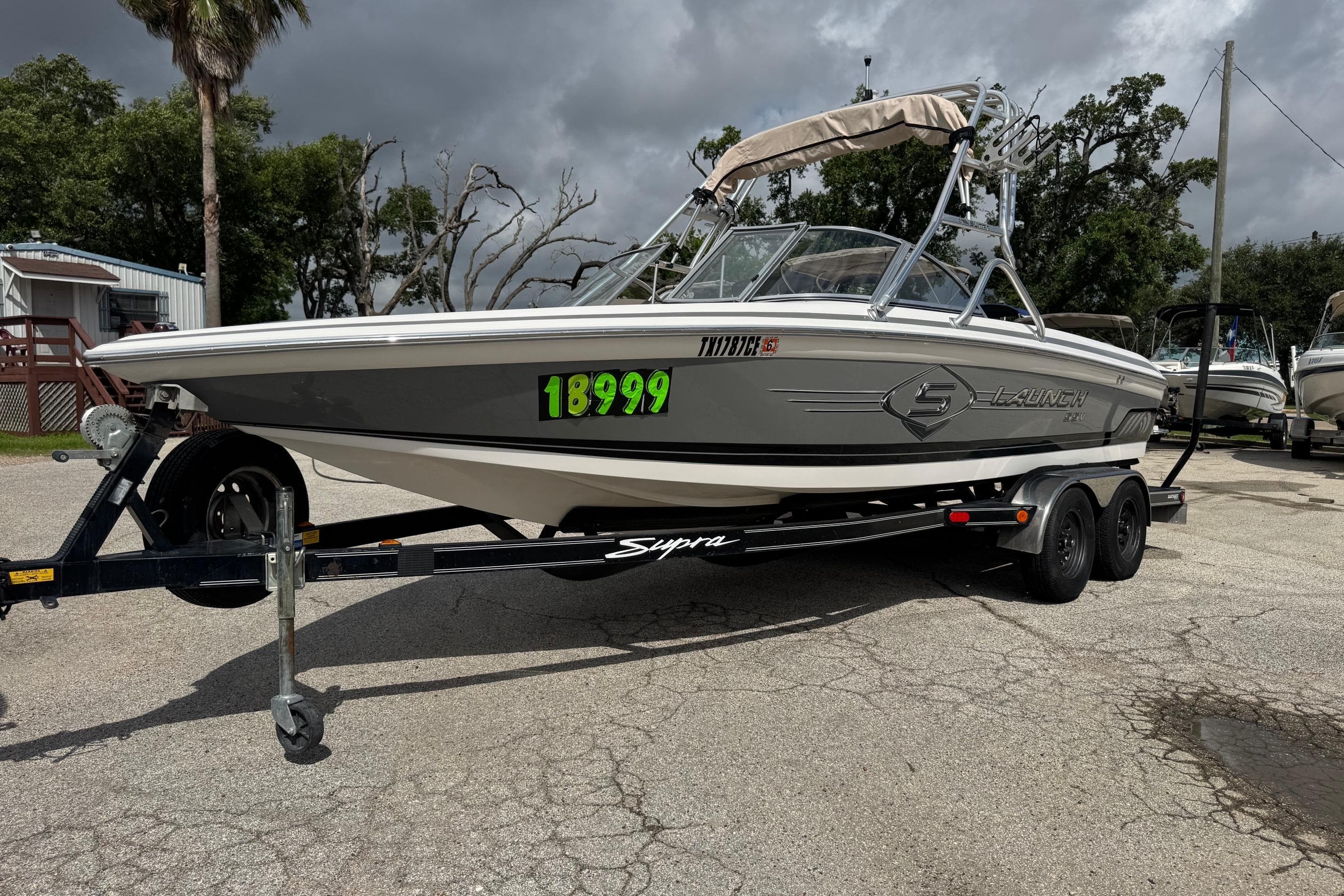 2002 Supra Launch 22 SSV boat on trailer, parked outdoors under cloudy sky.