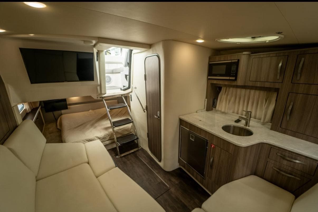 Luxurious interior of 2021 Regal 33 OBX boat with kitchenette and cozy seating area.