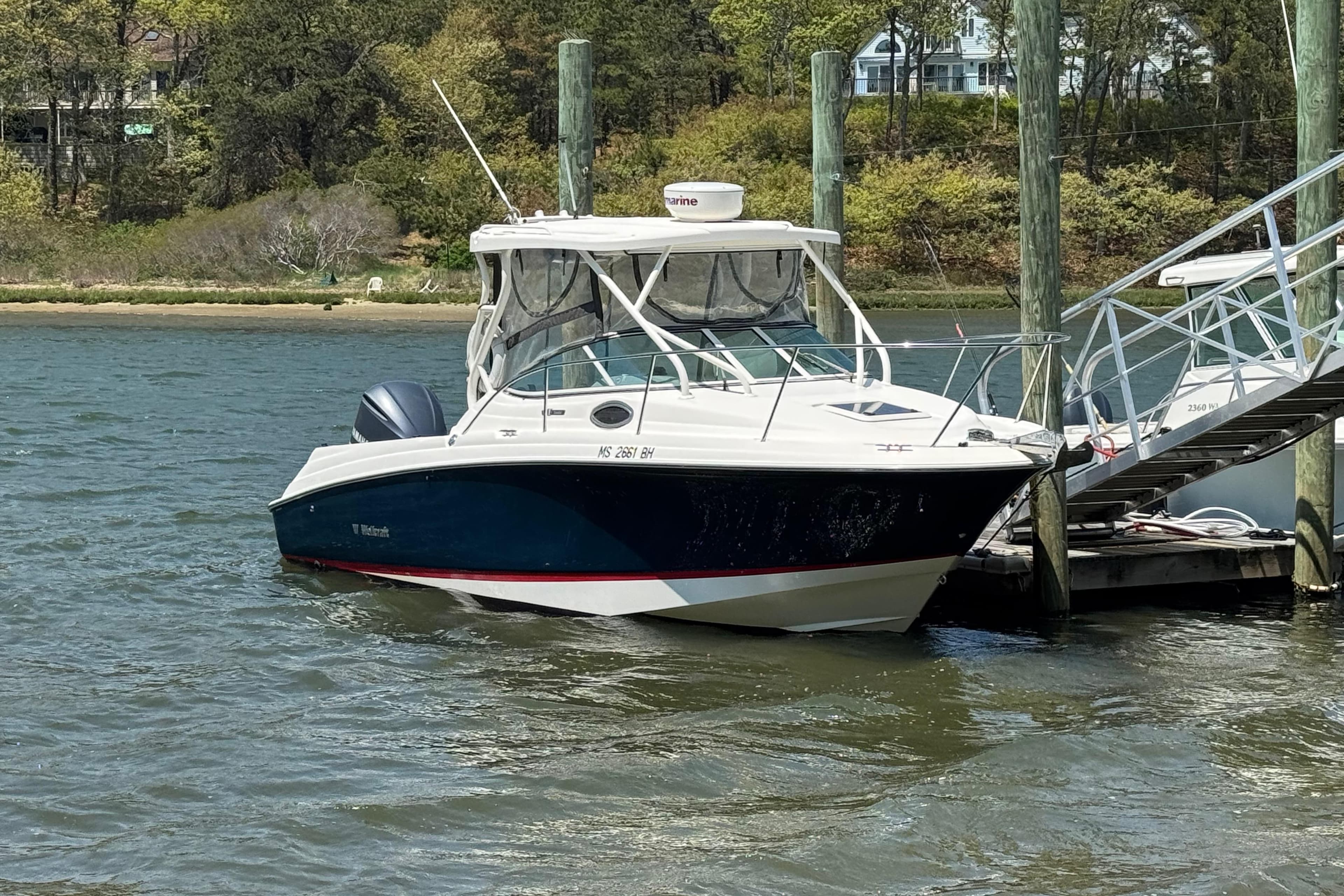 2016 Wellcraft 252 Coastal boat docked by a scenic shoreline.