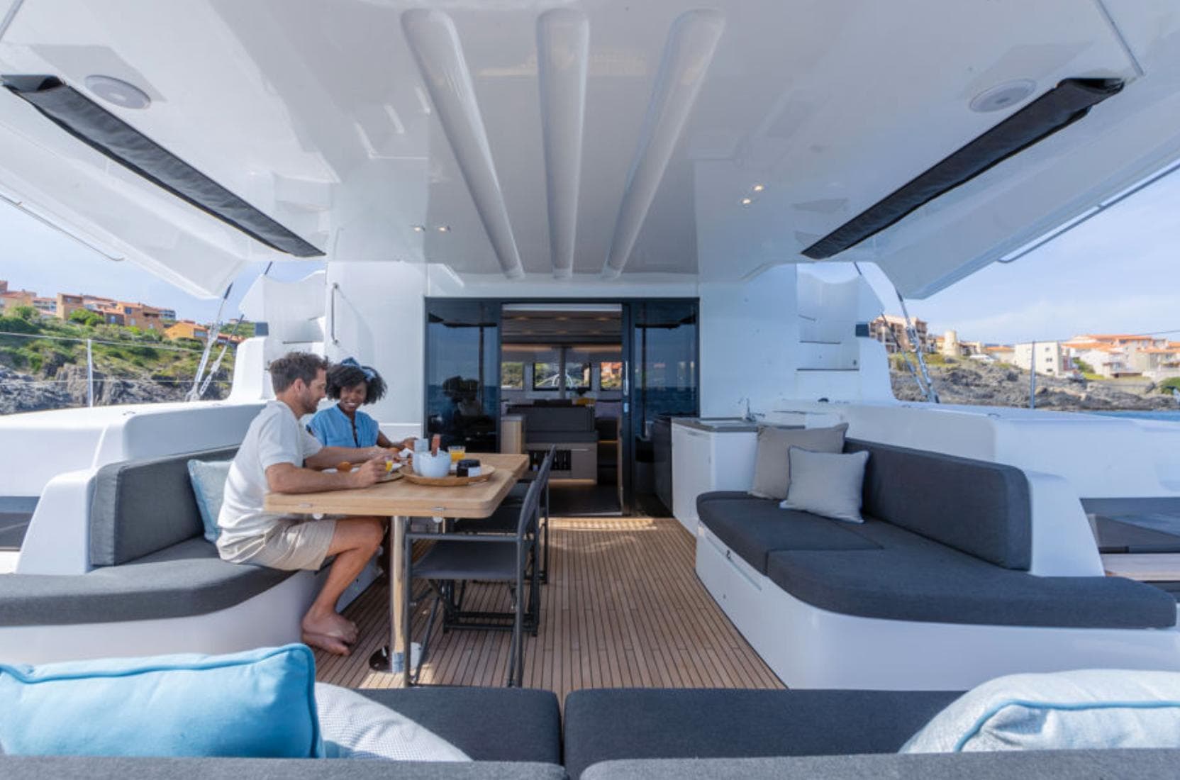 Couple dining on Lagoon 51 yacht's spacious deck, 2025 model, with modern seating and ocean view.