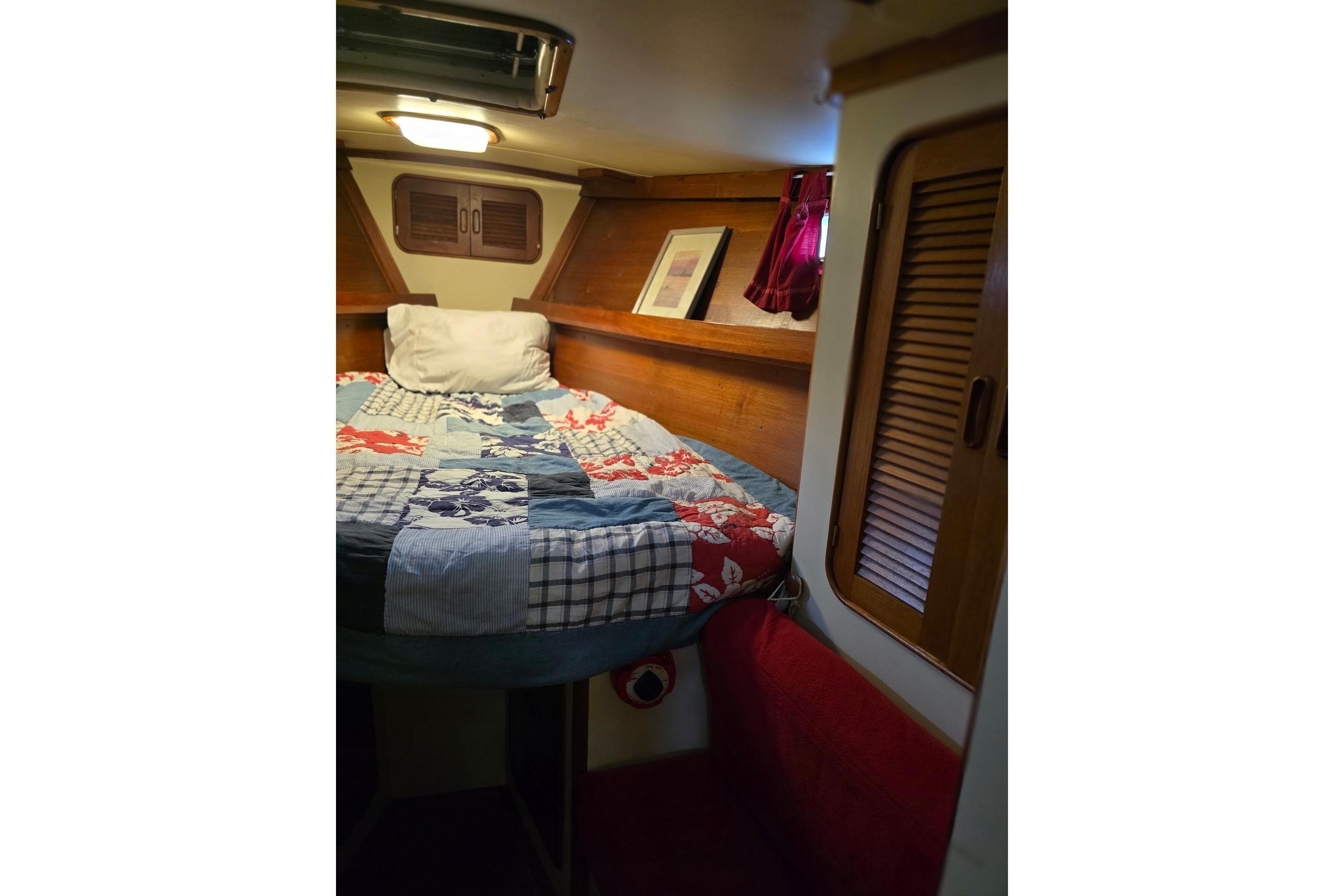 Cozy cabin interior of 1982 Irwin 52 sailboat with colorful bedding and wooden accents.
