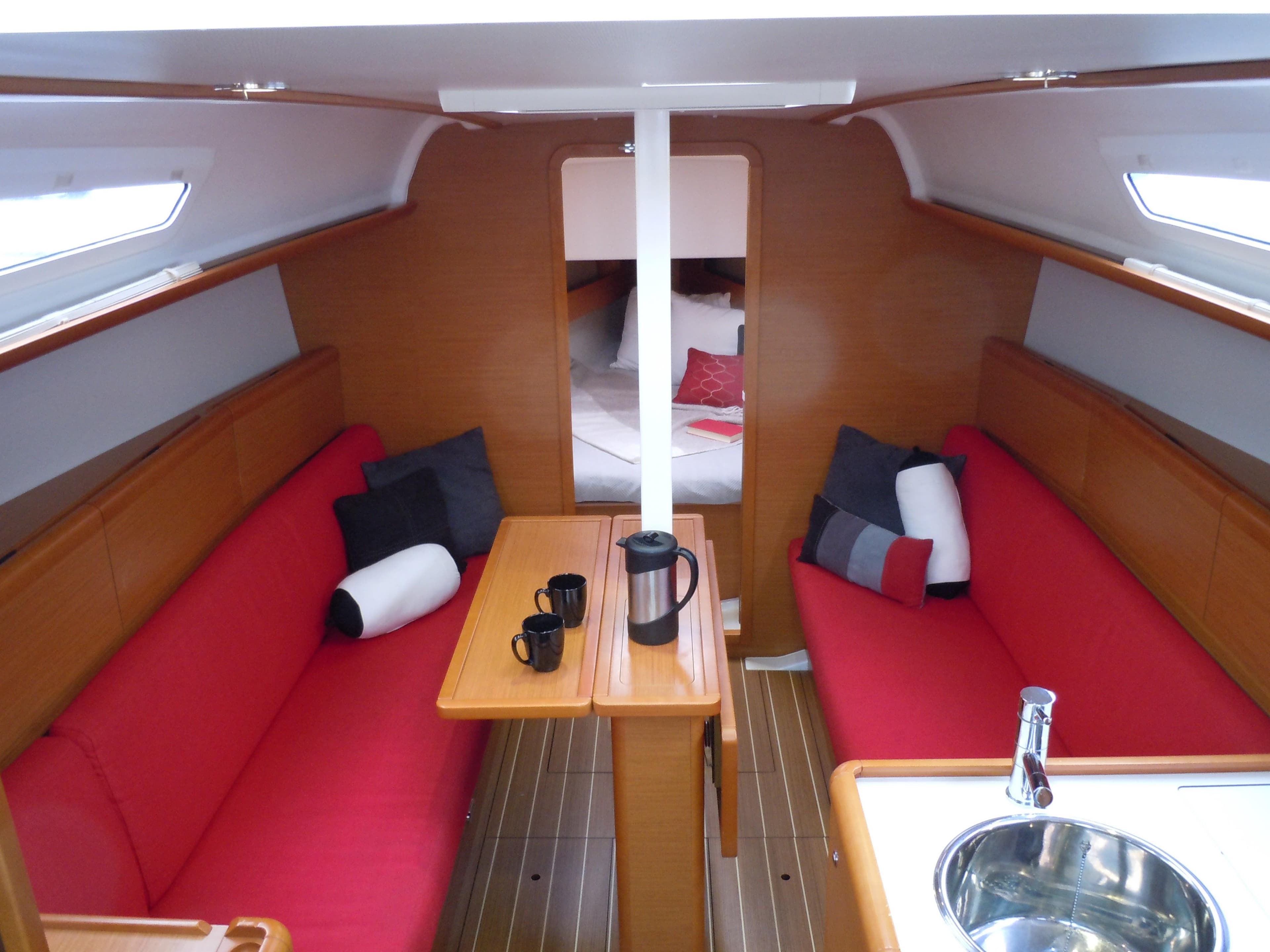 Interior of 2013 Jeanneau Sun Odyssey 33i sailboat with red seating and wooden finishes.