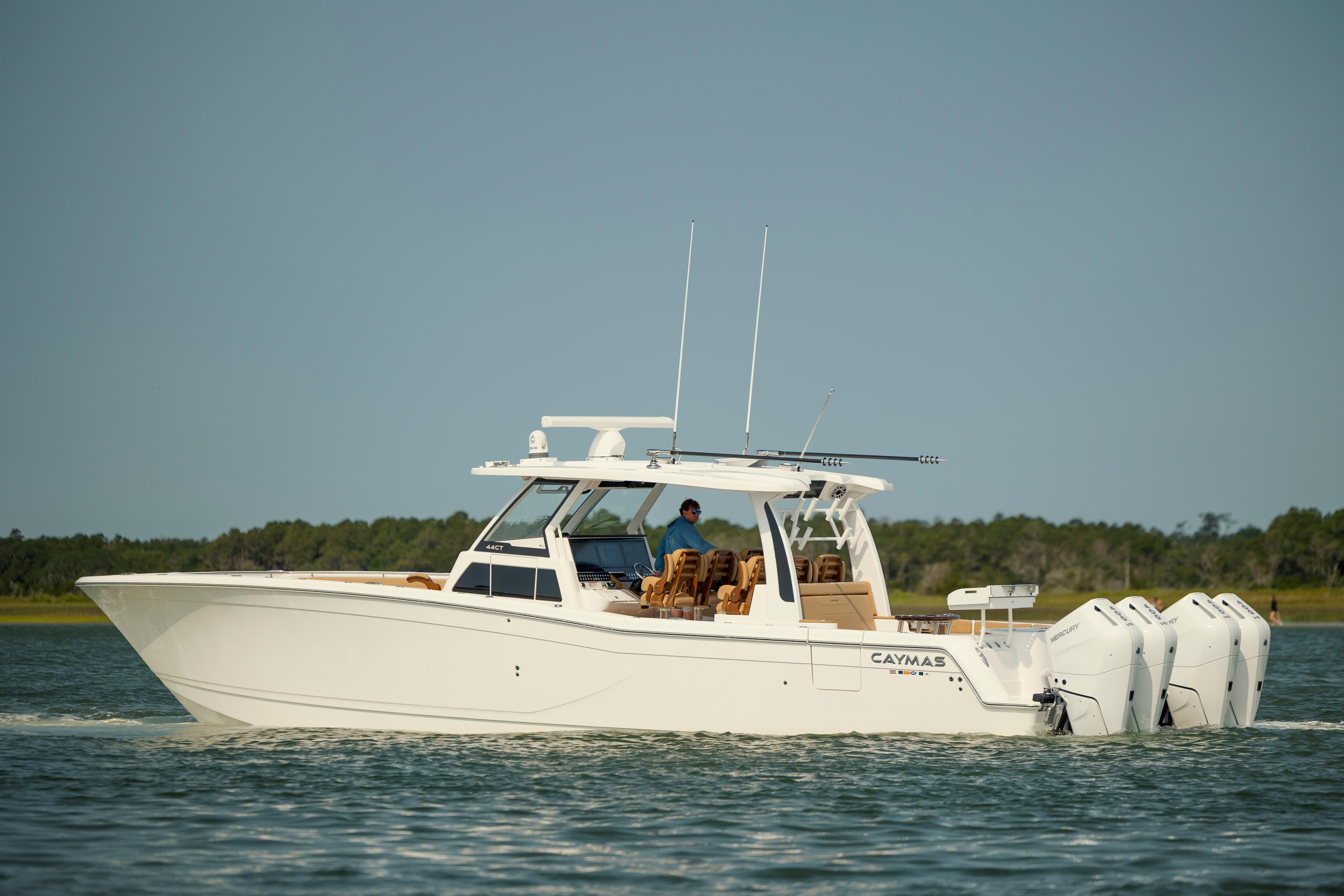 2025 Caymas 44 CT boat cruising on a calm lake with multiple outboard engines.