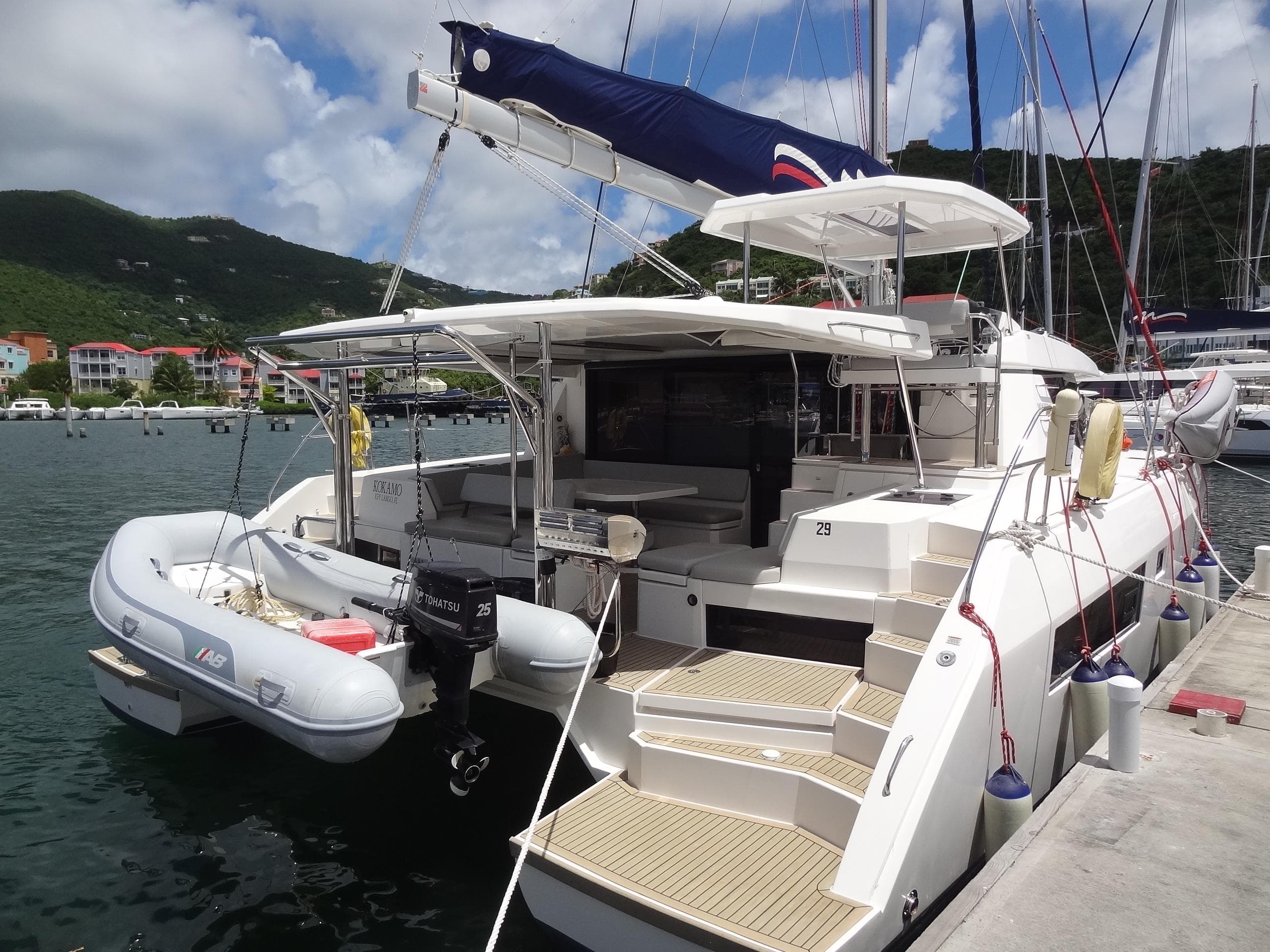 2020 Leopard 45 catamaran docked with inflatable dinghy, scenic marina background.