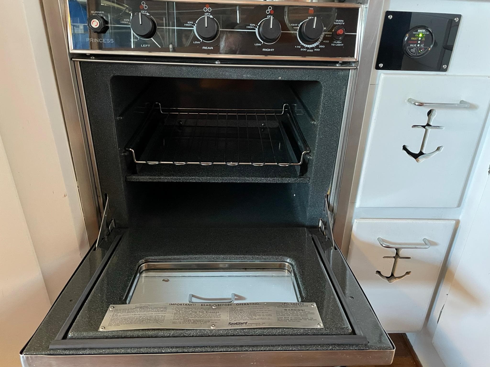 1961 Chris-Craft Conqueror oven with open door, control knobs, and anchor-themed cabinetry.