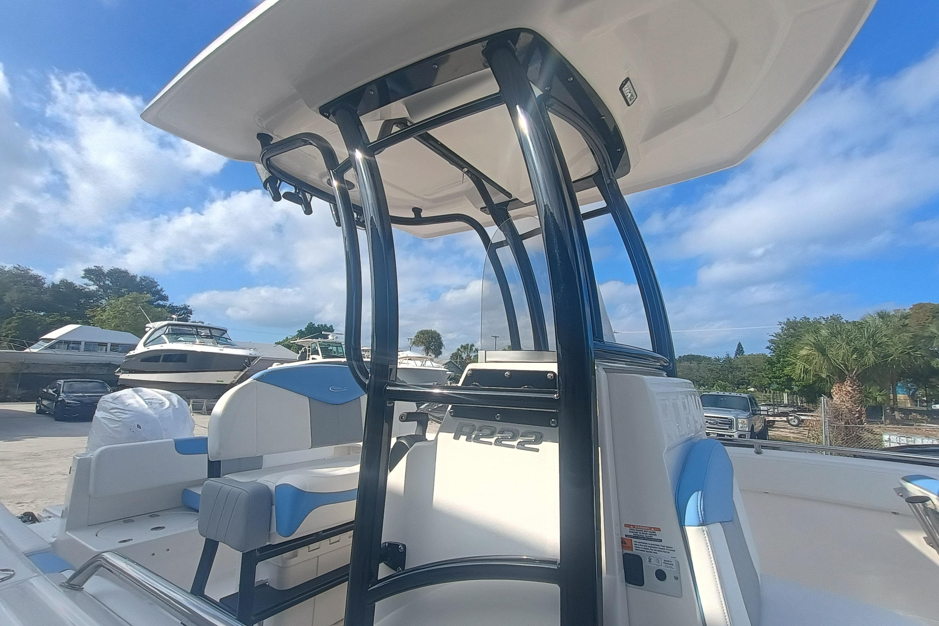2026 Robalo R222 Center Console boat with T-top and seating, docked under blue sky.
