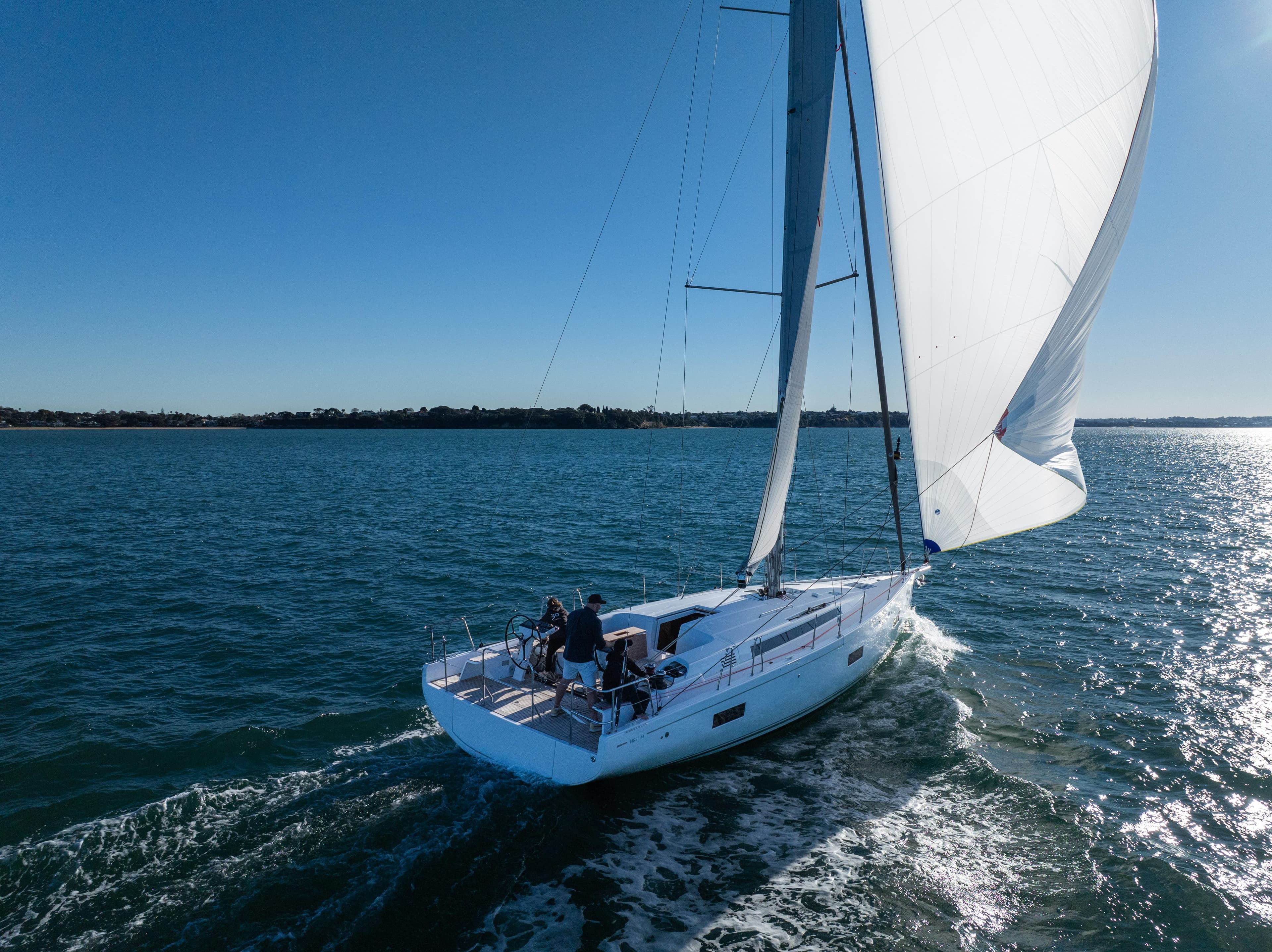 2024 Beneteau First 44 sailing on open water under clear blue skies.
