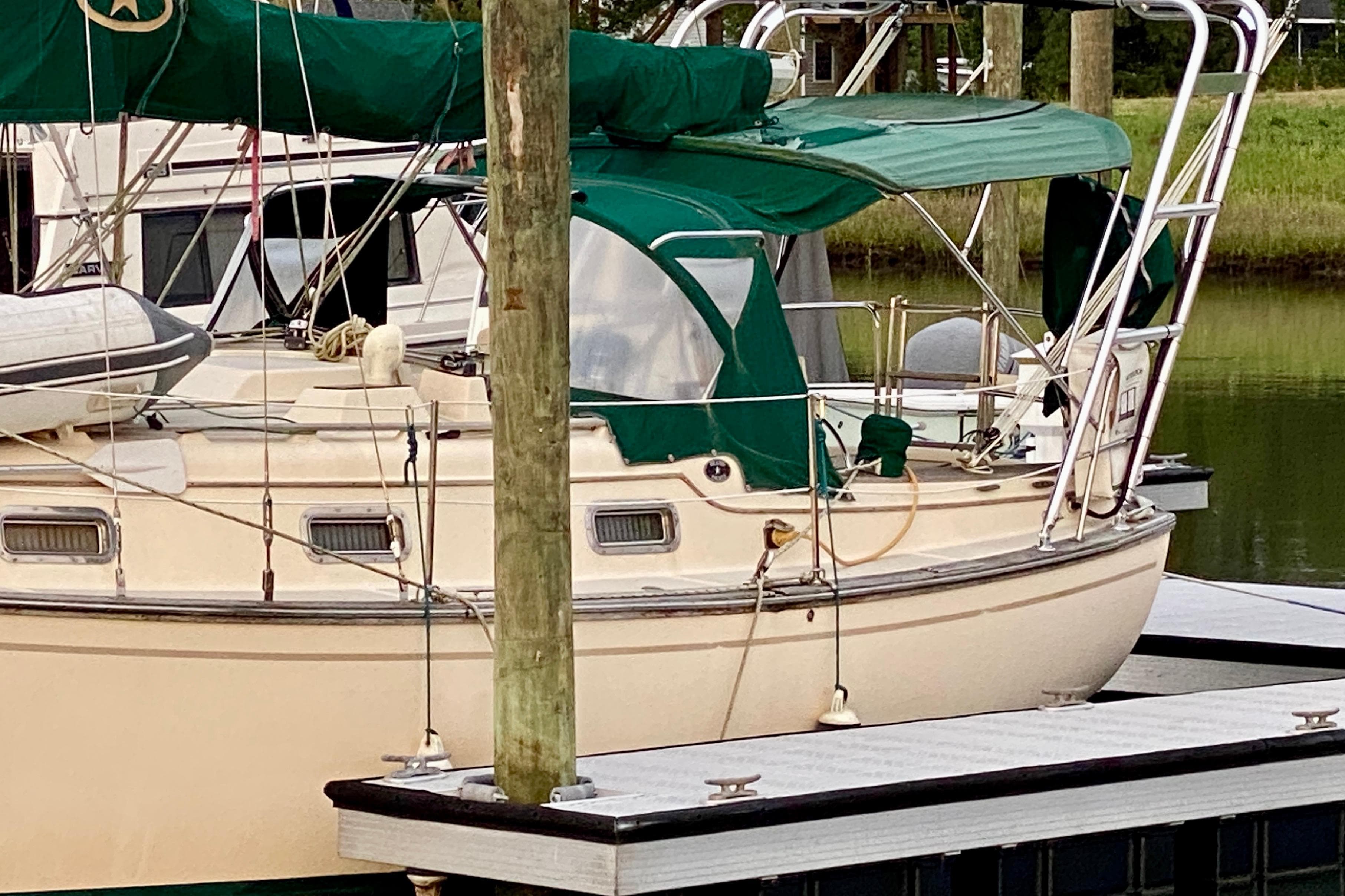 1992 Island Packet 29 sailboat docked with green canopy and polished deck.