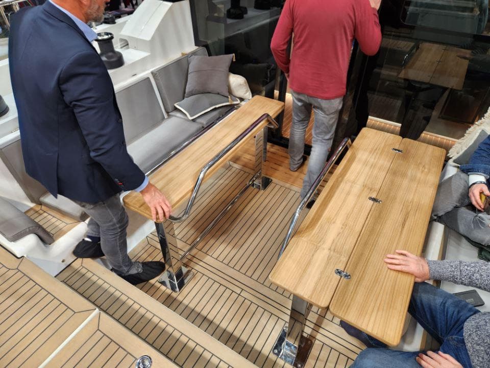 Interior of 2025 Moody 48 DS yacht with wooden tables and seating area.