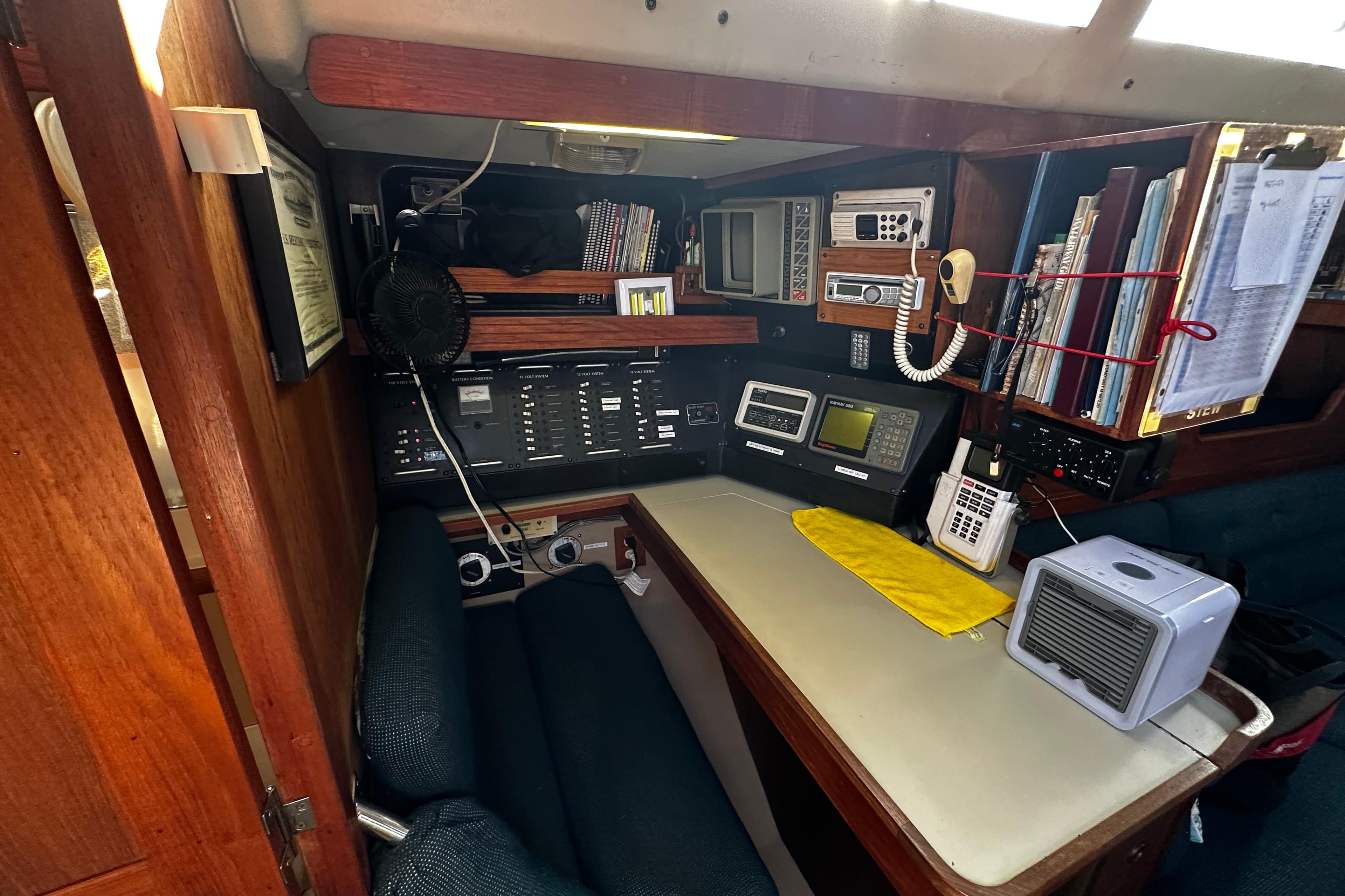 Navigation station inside a 1988 C&C 44 sailboat, featuring communication equipment and storage.