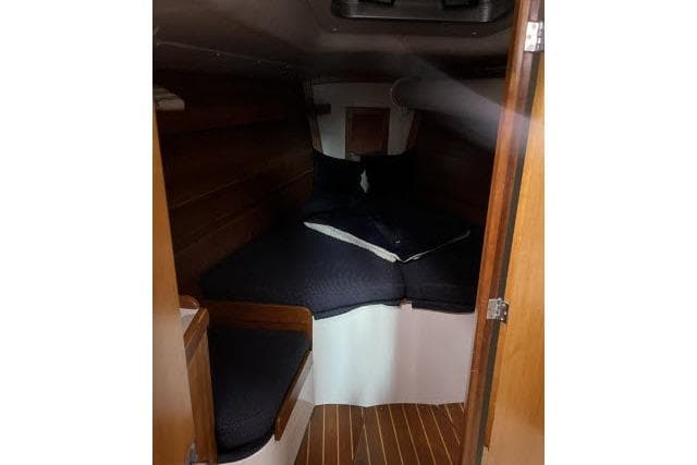 2004 J Boats J/133 cabin interior with wooden finish and cozy bedding.