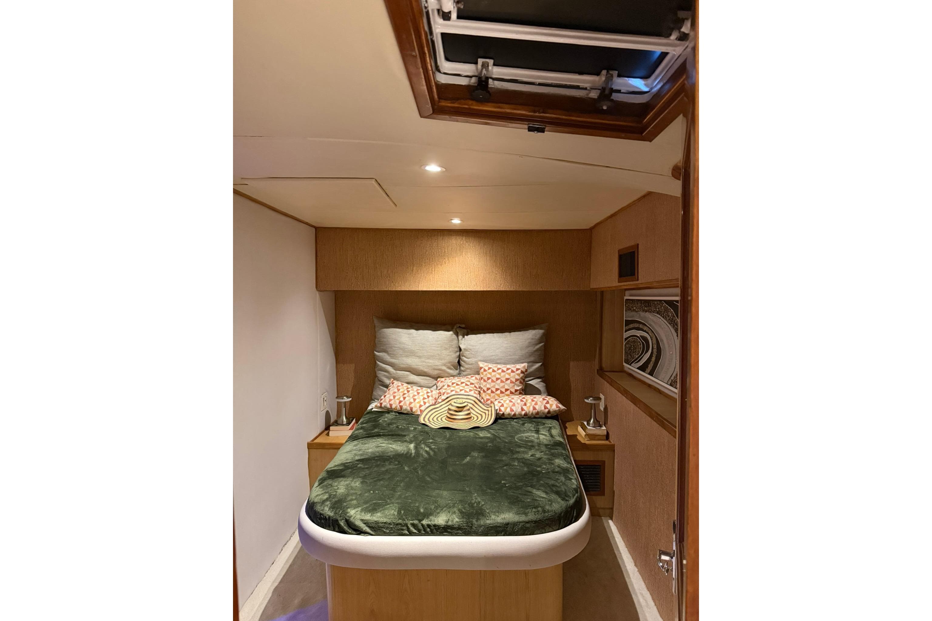 Cozy bedroom interior of 1989 Buddy Davis 61 yacht with plush bedding and warm lighting.