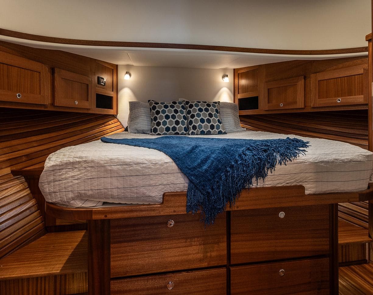 Cozy cabin interior of 2026 American Tug 395 with wooden finish and comfortable bedding.