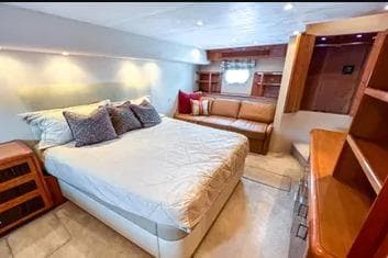 Luxurious bedroom interior of 2007 Hatteras 68 Convertible yacht with cozy bed and seating area.