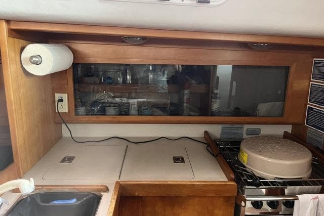 2004 J Boats J/133 yacht kitchen with wooden cabinetry and stove.