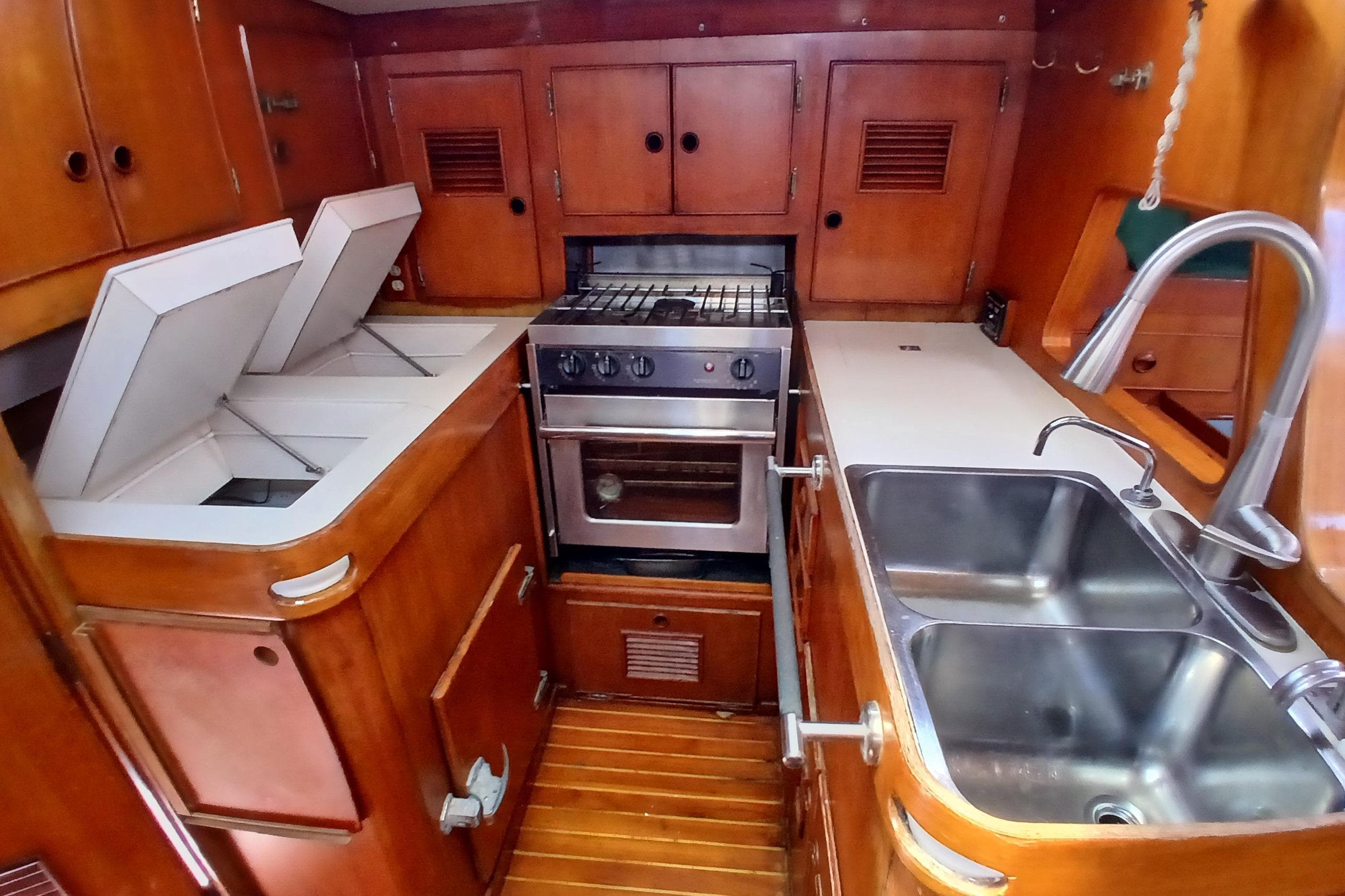 Vintage 1981 SKYE 51 yacht kitchen with wooden cabinetry and stainless steel sink.