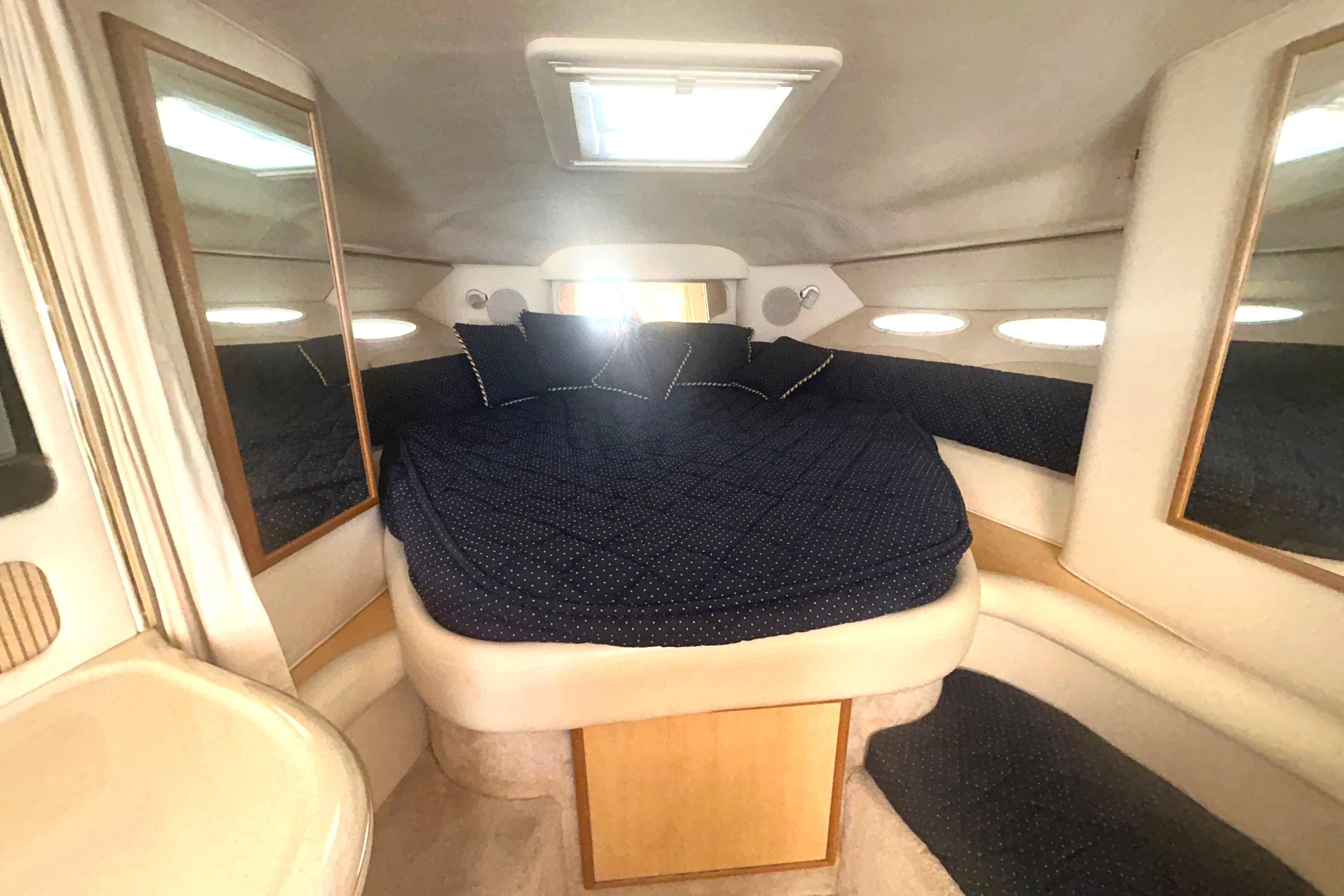 Interior cabin of 2000 Sea Ray 340 Sundancer with cozy bed and mirrors.