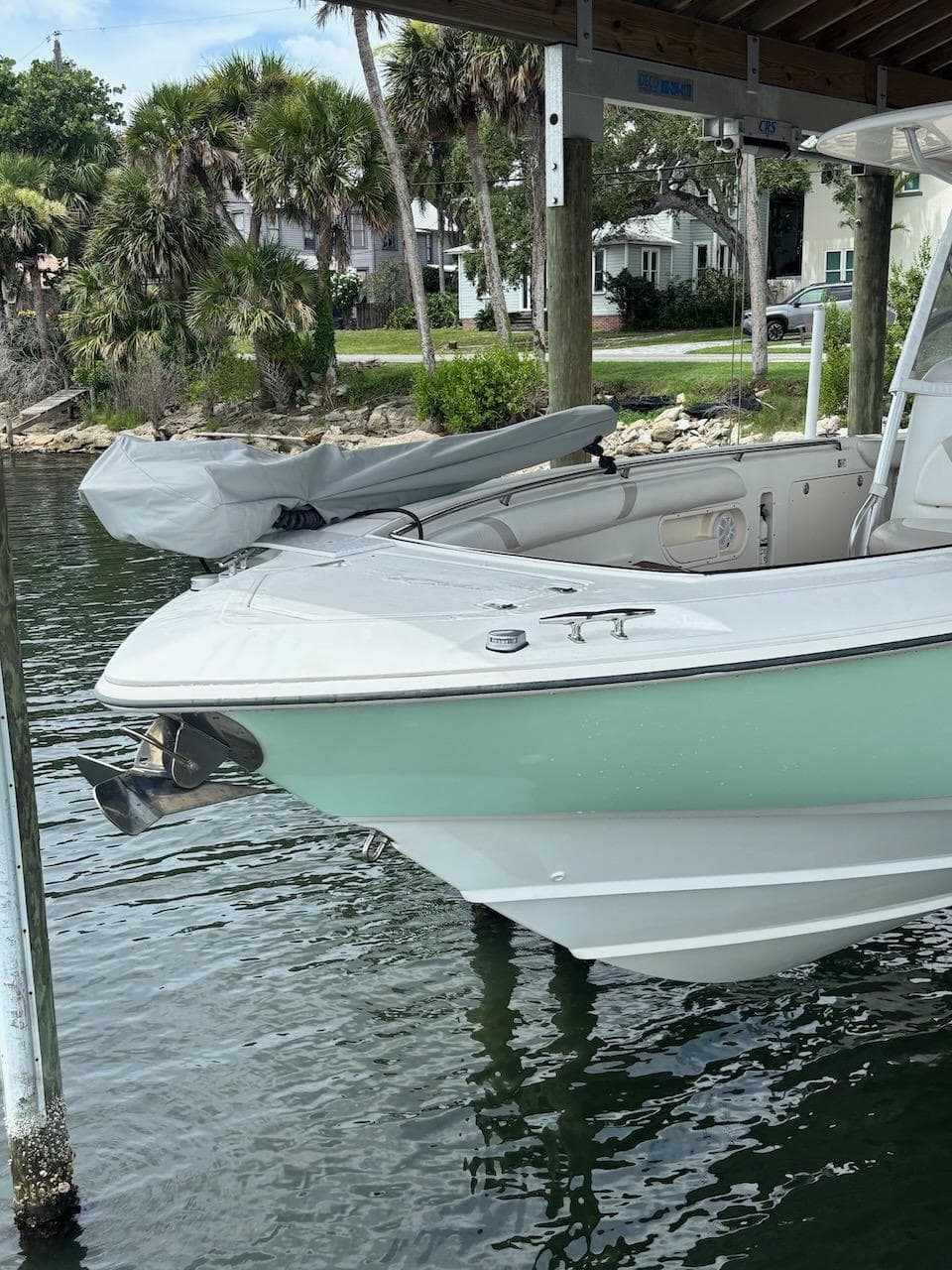 2006 Boston Whaler 320 Outrage boat docked near palm trees and waterfront homes.