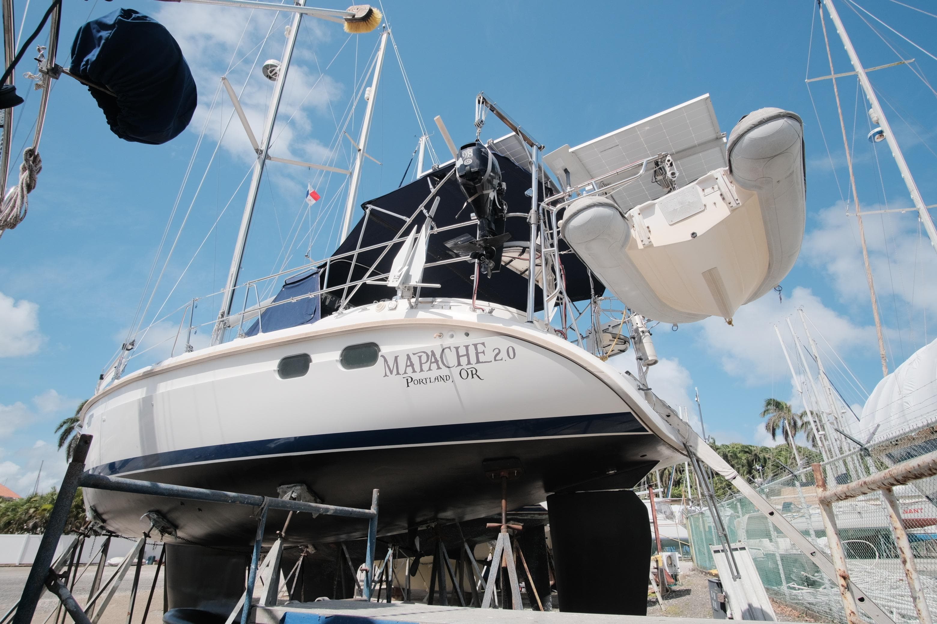 Hunter 376 sailboat from 1996 on stands, with dinghy and solar panels, under clear sky.