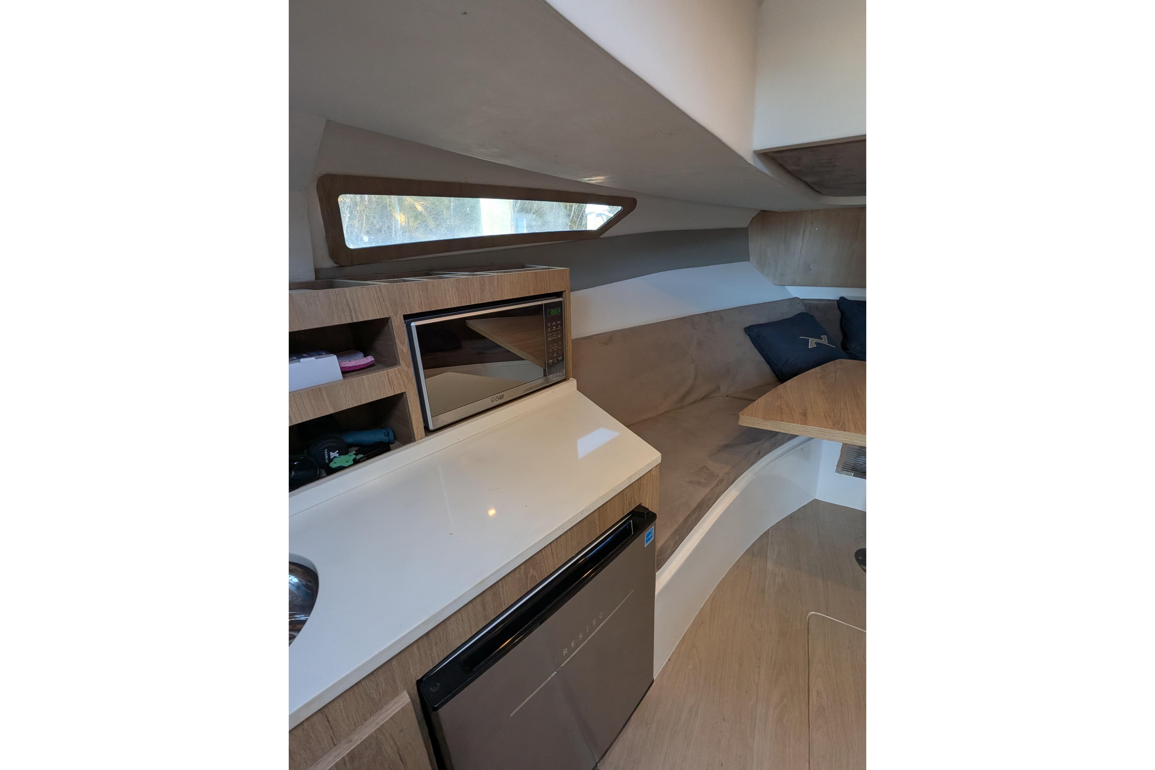 2023 NX Boats 340 Sport Coupe interior with kitchenette and seating area.