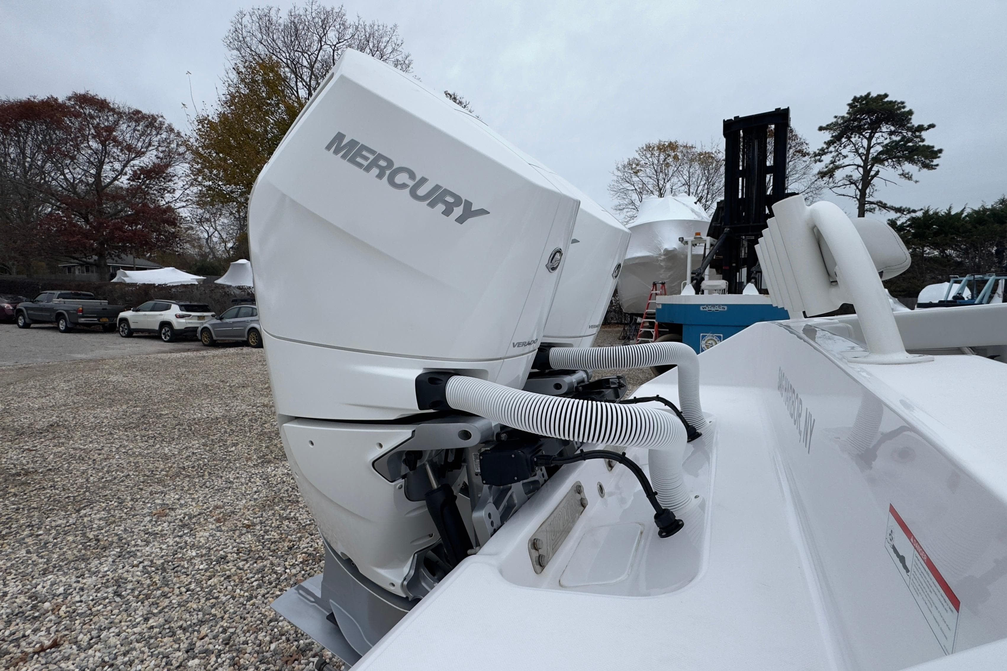 2024 Jupiter 32 FS boat with Mercury outboard engine in a gravel lot.